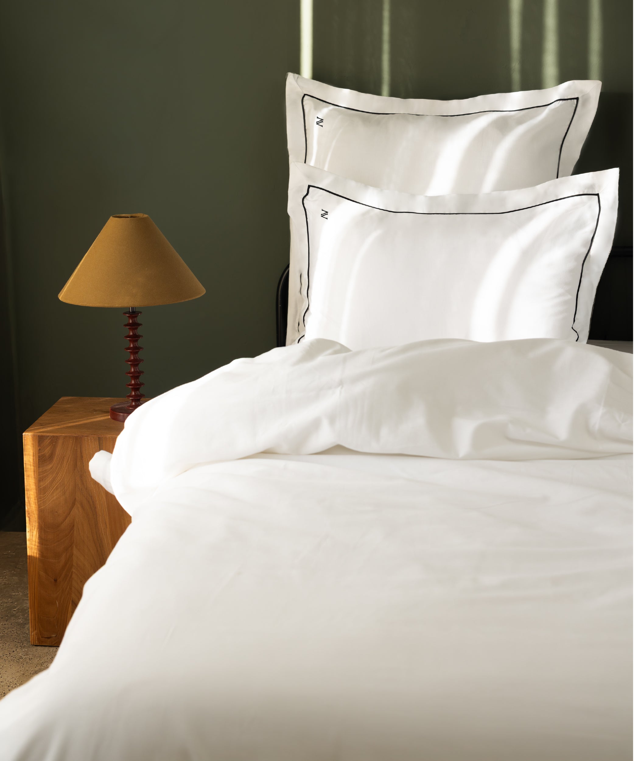 Luxury Cotton Sateen Oxford Duvet Cover Set with black contrast piping on a bed with amber bedside lamp – Limasso London