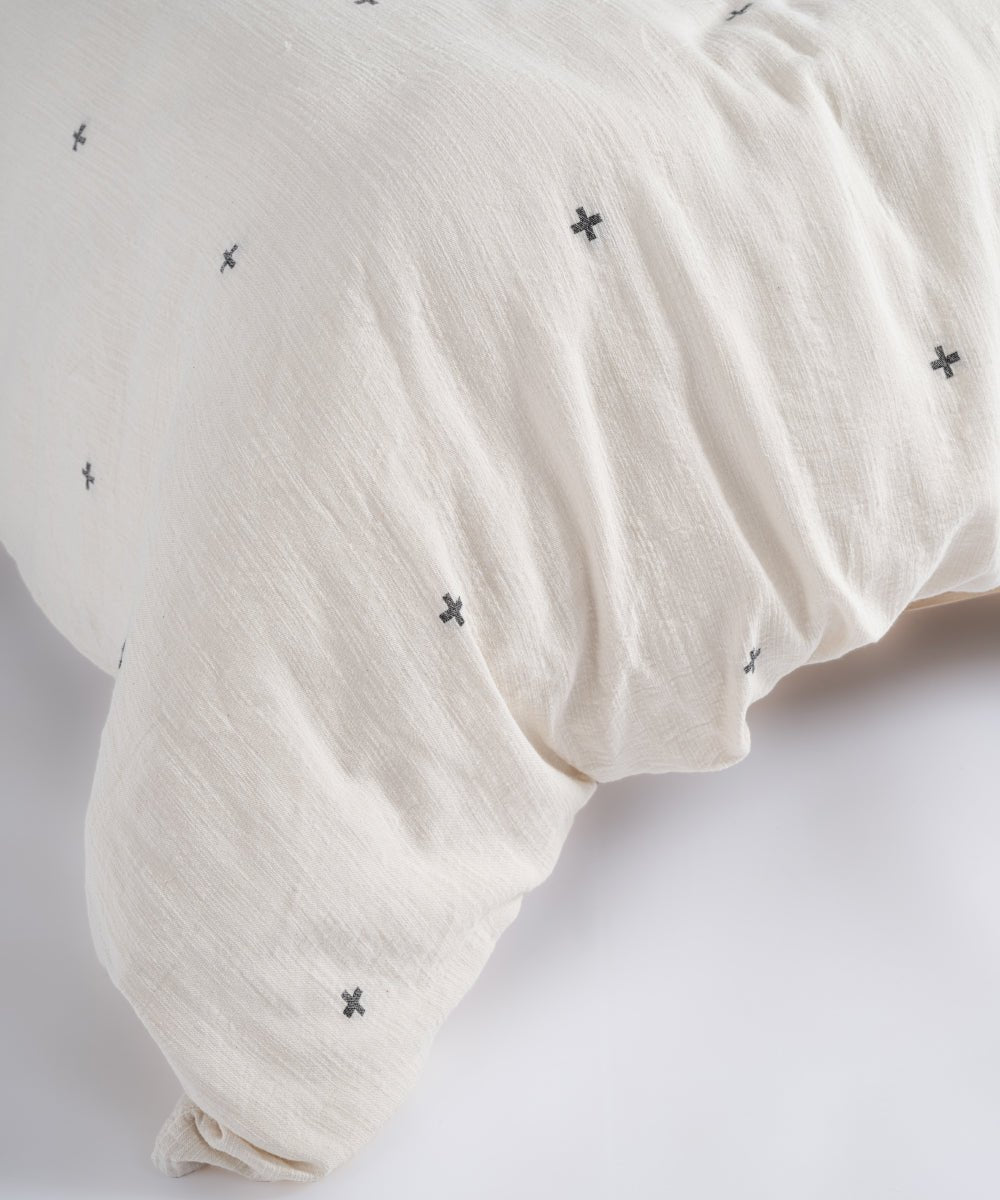 Close-up texture of breathable 100% cotton fabric with black cross pattern on natural cream base