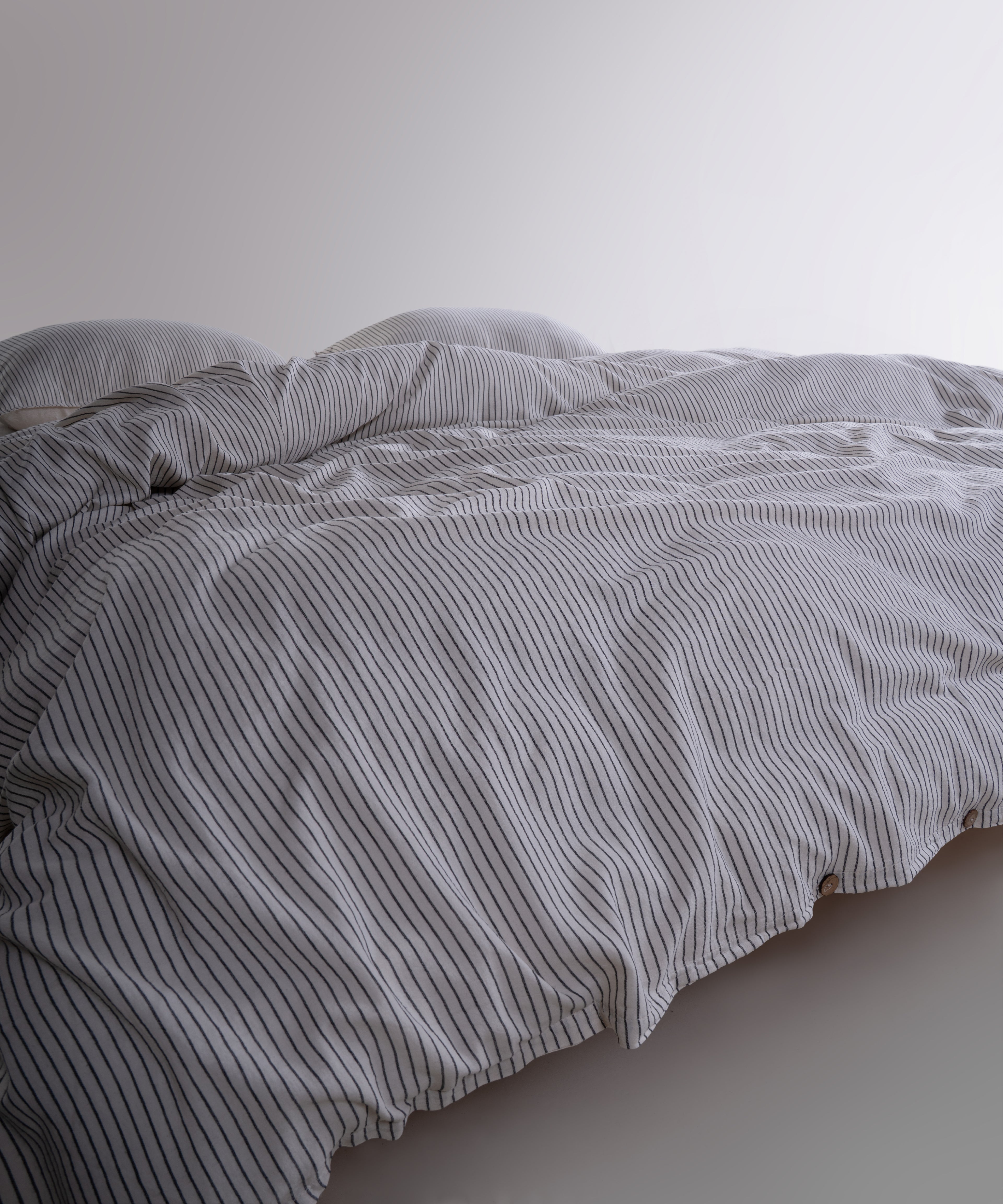 Close-up of 100% cotton garment washed fabric showing natural cream texture with fine black stripes