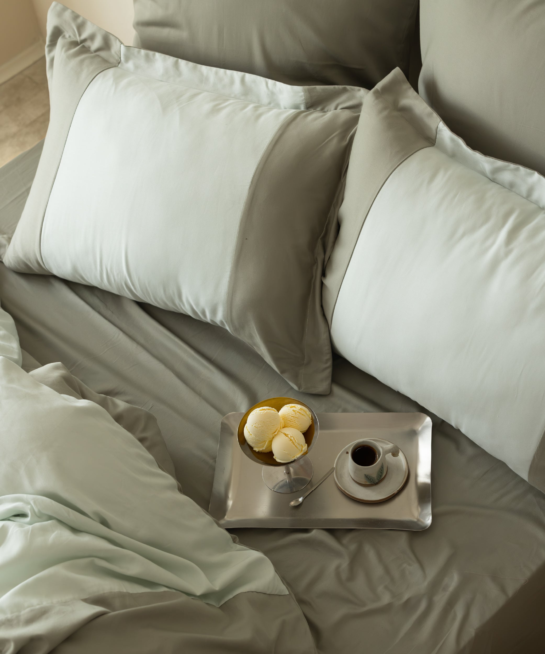 Overhead view of 210TC Sateen Duvet Set Mineral Green and Mint with breakfast tray and coffee on the bed – Limasso London