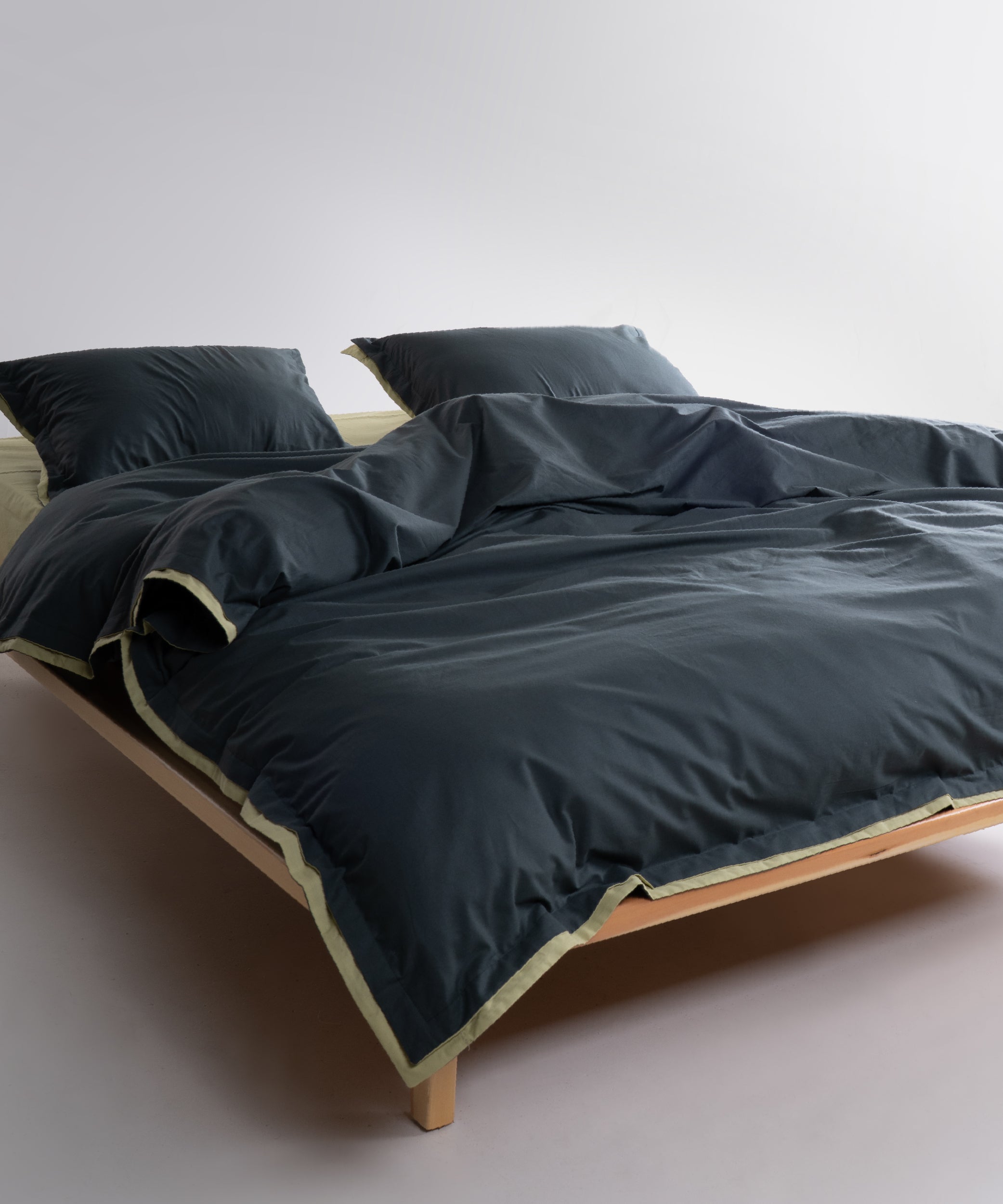 Dark green cotton pillowcases with pistachio trim and envelope closure detail