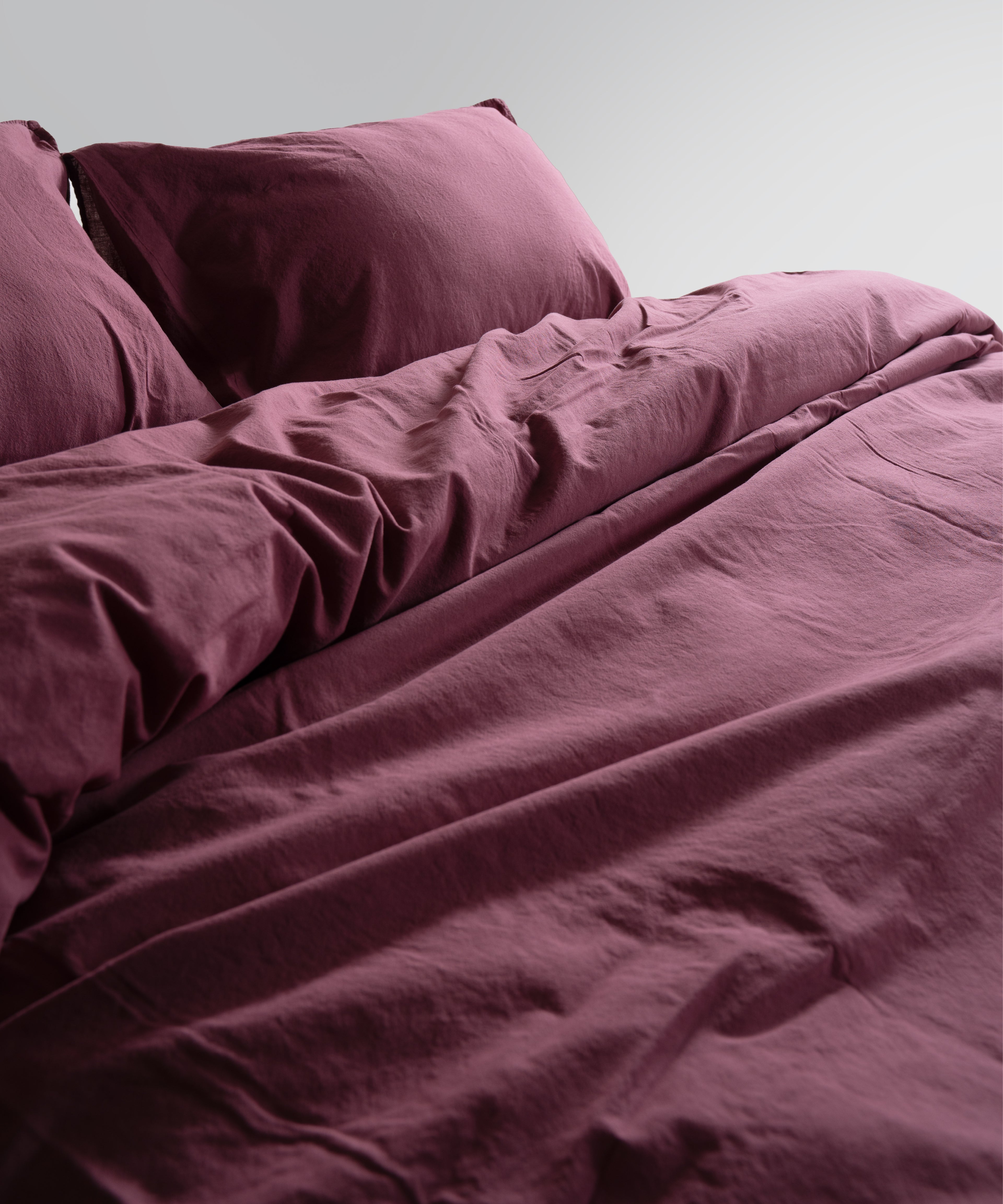 Raspberry pillowcases styled on bed to add a rich, warm and modern touch. Stonewashed cotton texture creates a relaxed premium finish.