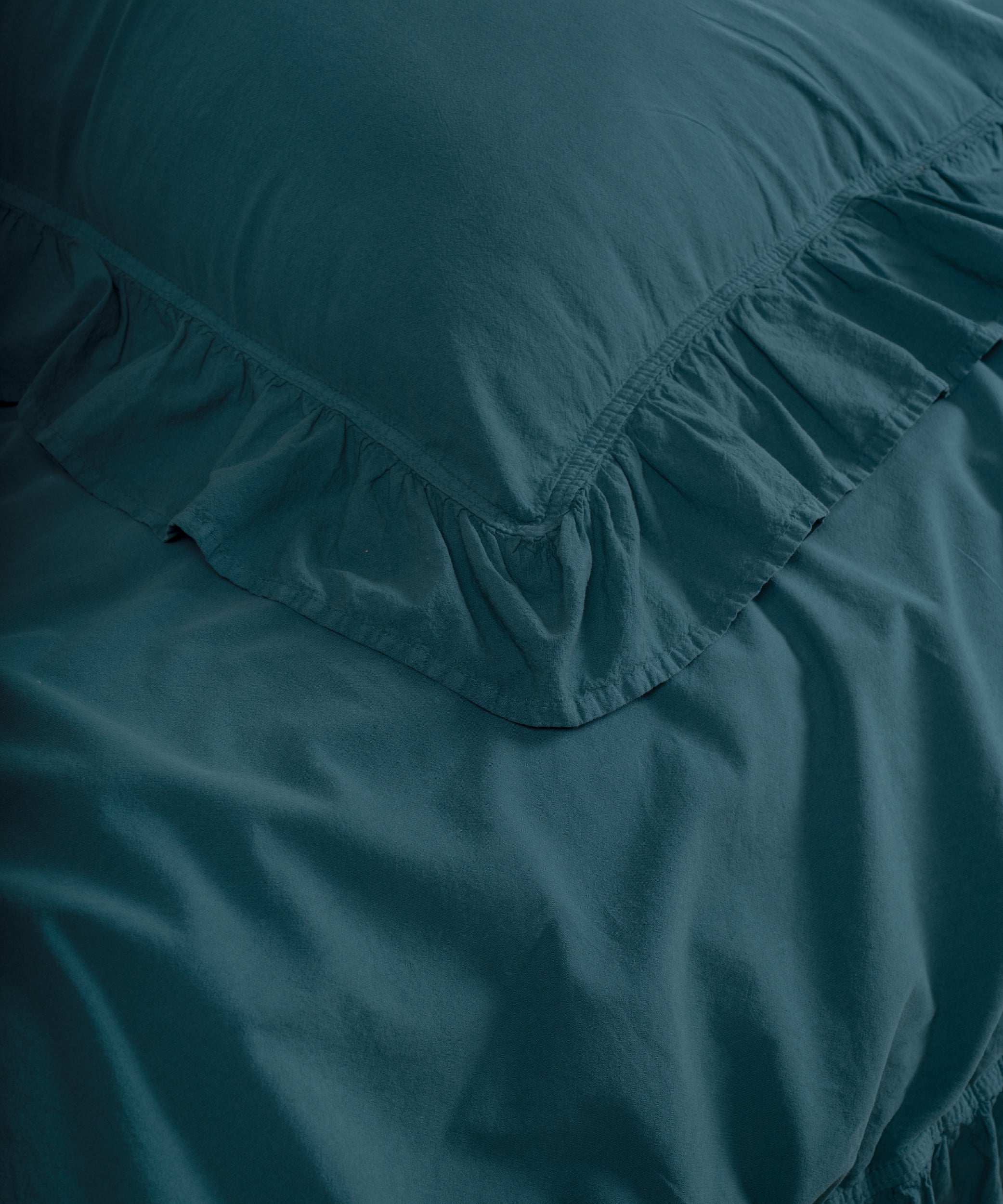 Close-up of ruffled edges on dark green stonewashed cotton pillowcase with double-needle stitching