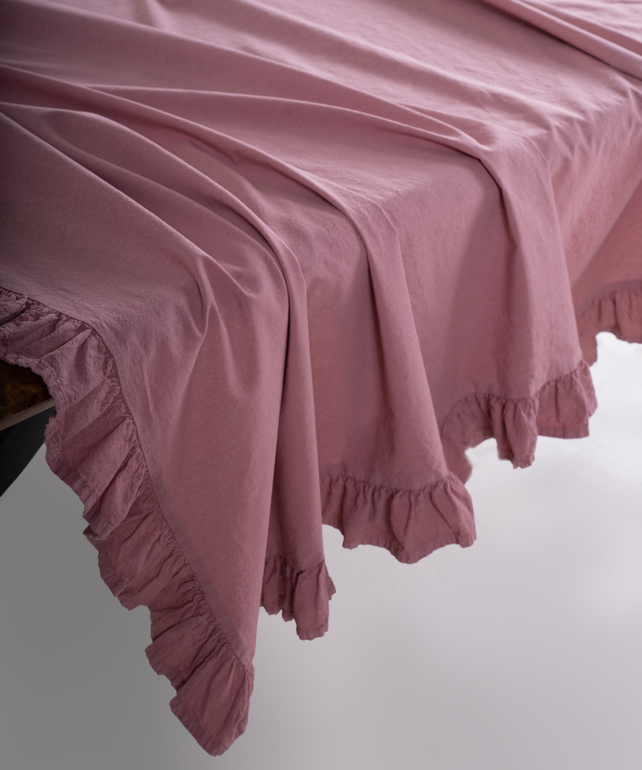 Close up of Old Rose pink stonewashed cotton tablecloth showing soft texture and ruffled edge detail, premium UK table linen