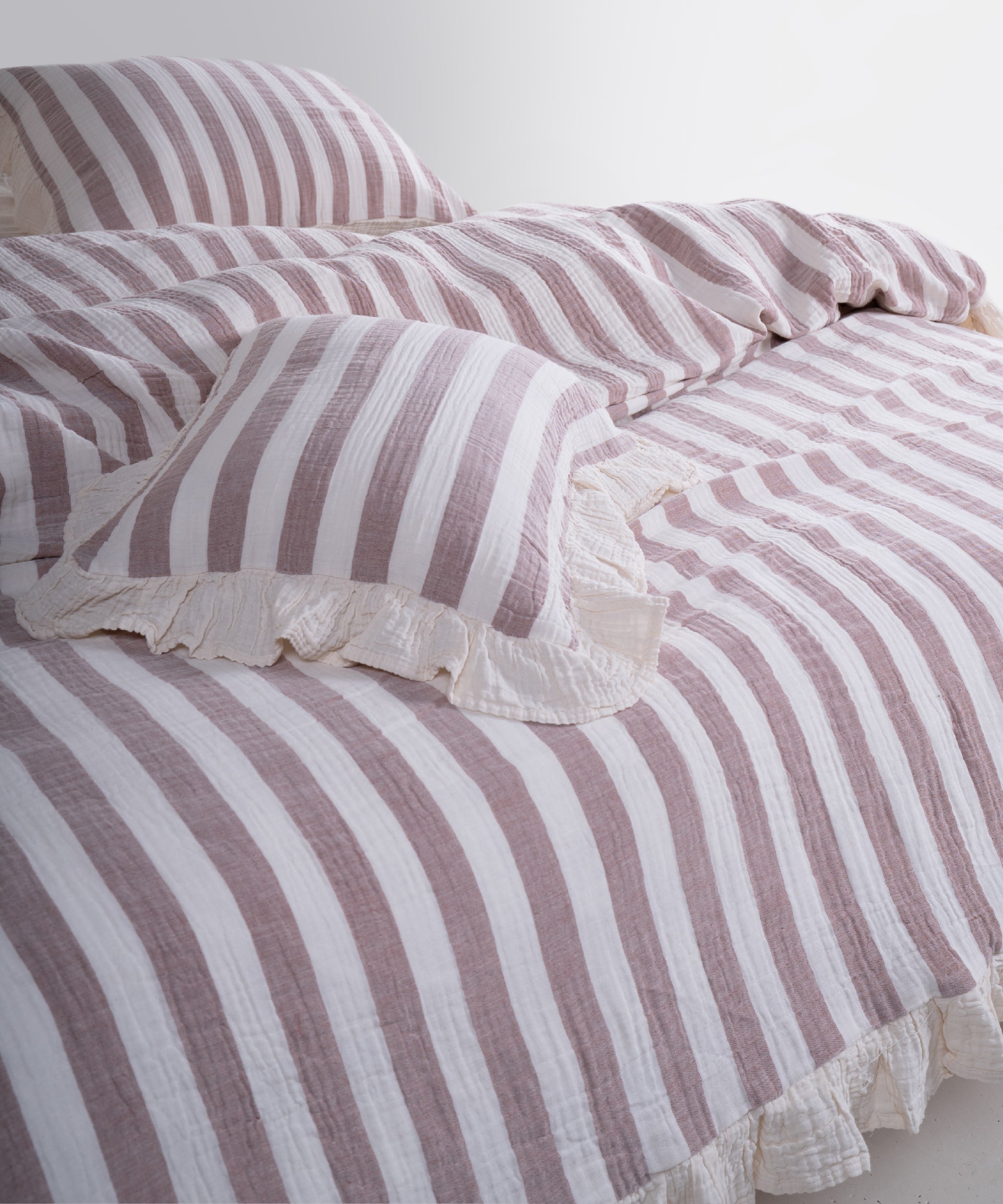 Close-up of yarn dyed 100% cotton muslin fabric with garment washed finish, natural cream base with bold brown stripes