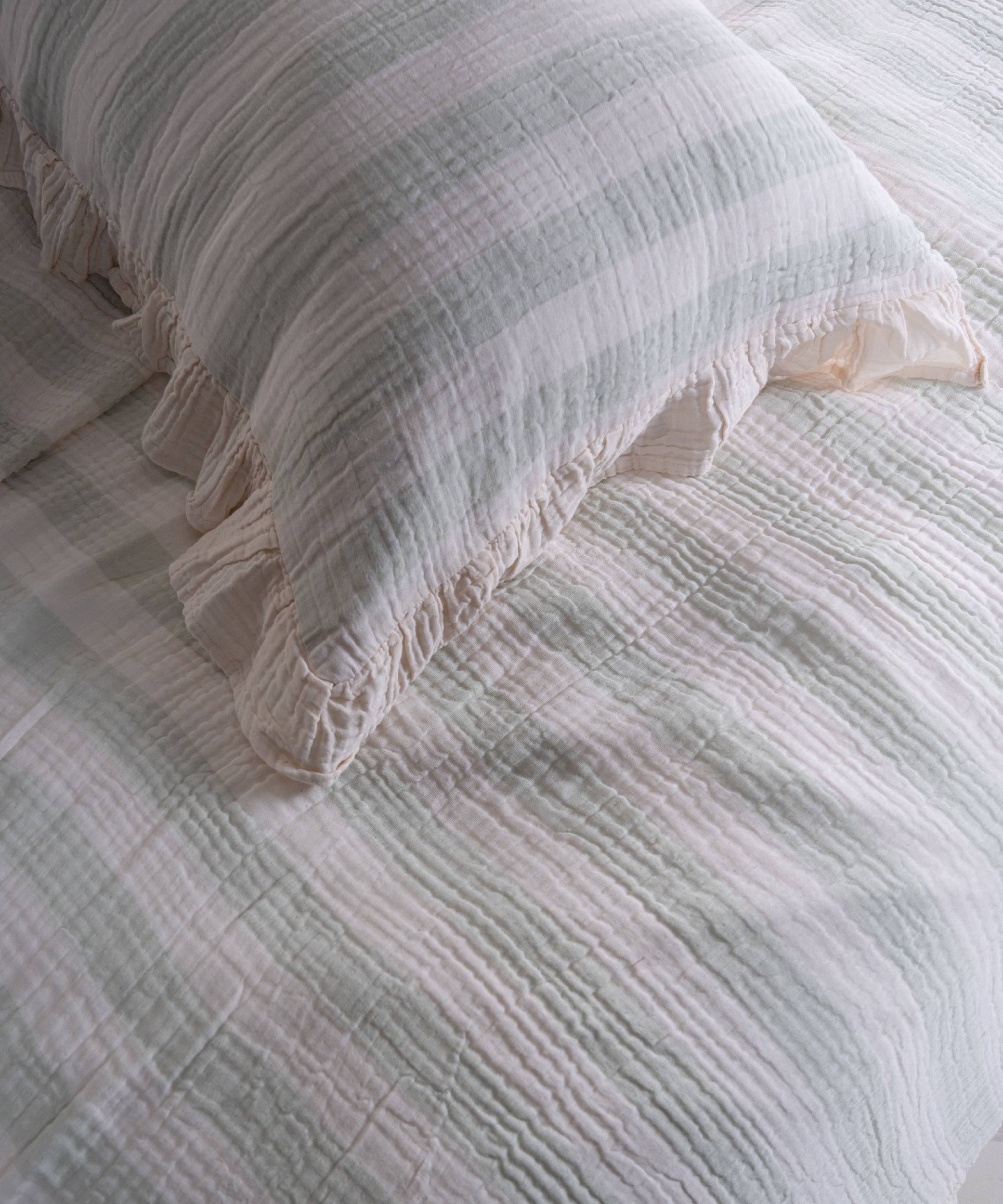 Close-up of yarn dyed 100% cotton muslin fabric with garment washed finish, natural cream base with mint stripes