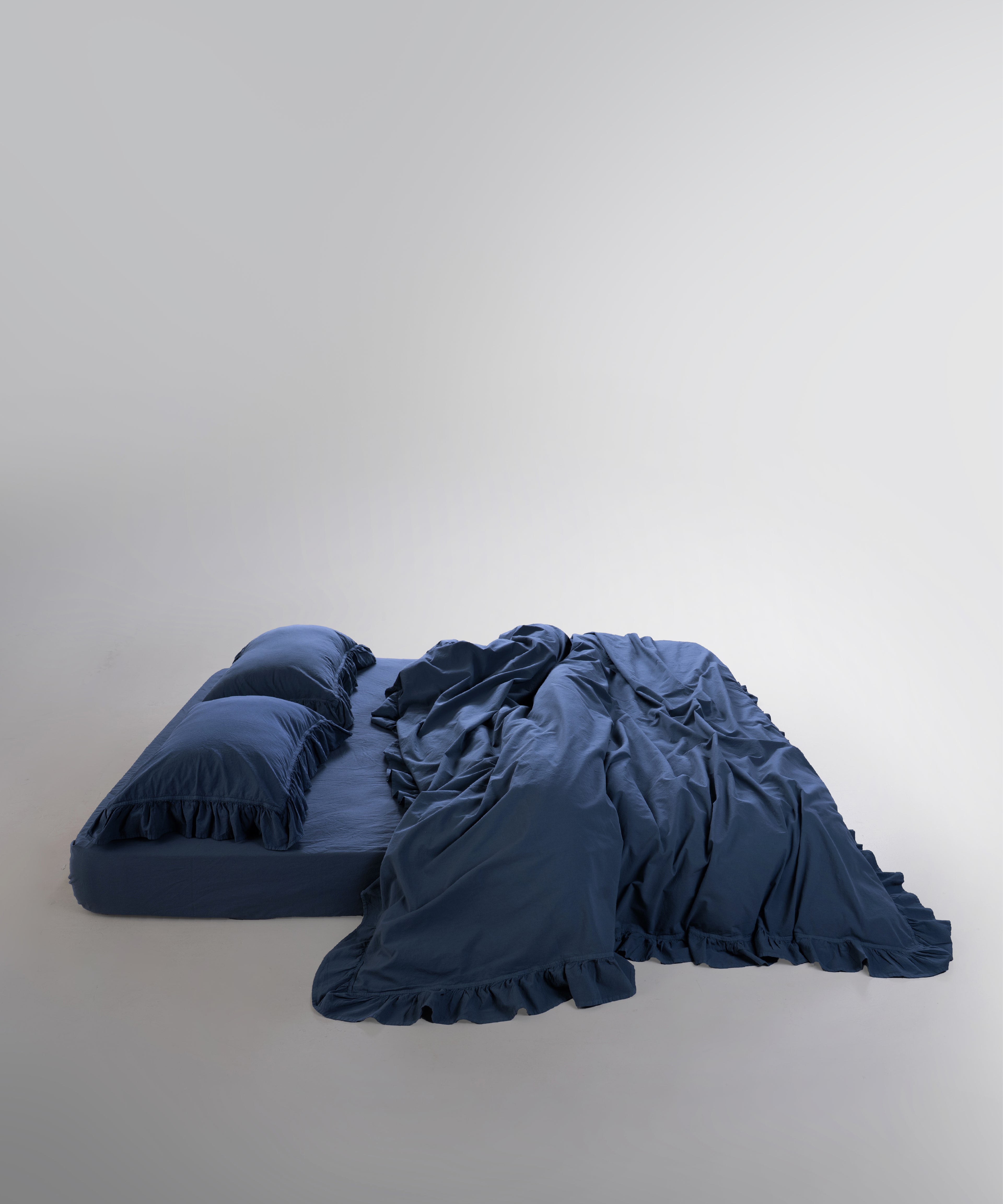 Double-stitched edges and ruffle detailing on dress blue cotton duvet cover