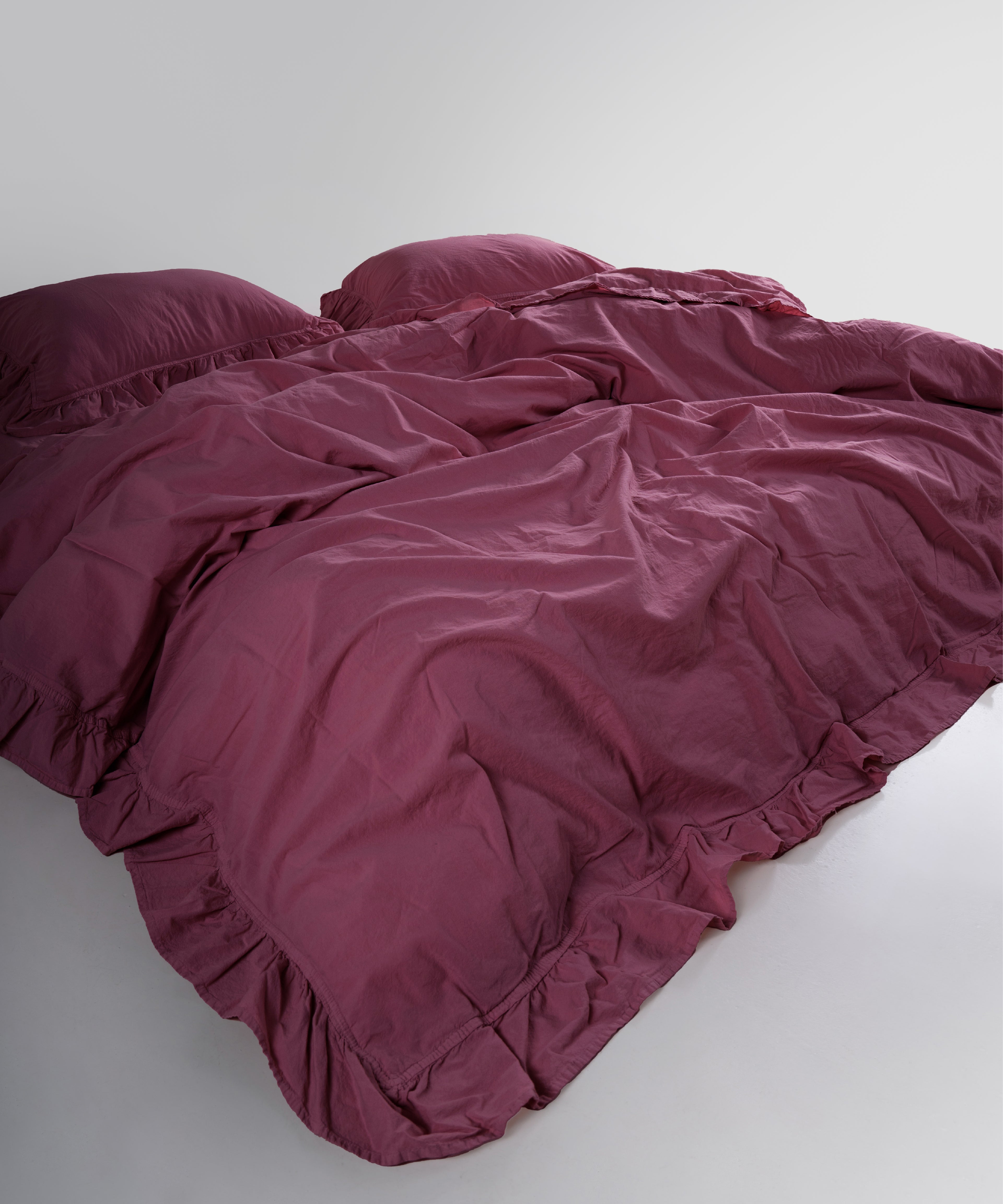 Ruffled edge detail of raspberry cotton duvet cover set with stonewashed finish