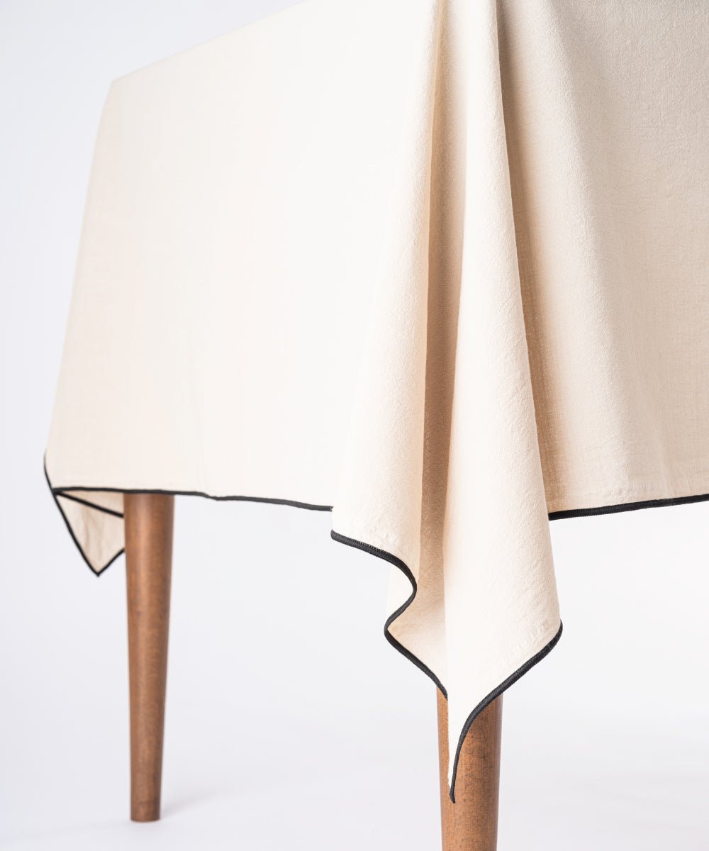 Beige embroidered cotton tablecloth styled on dining table with plates and decor, rectangular kitchen table cover UK