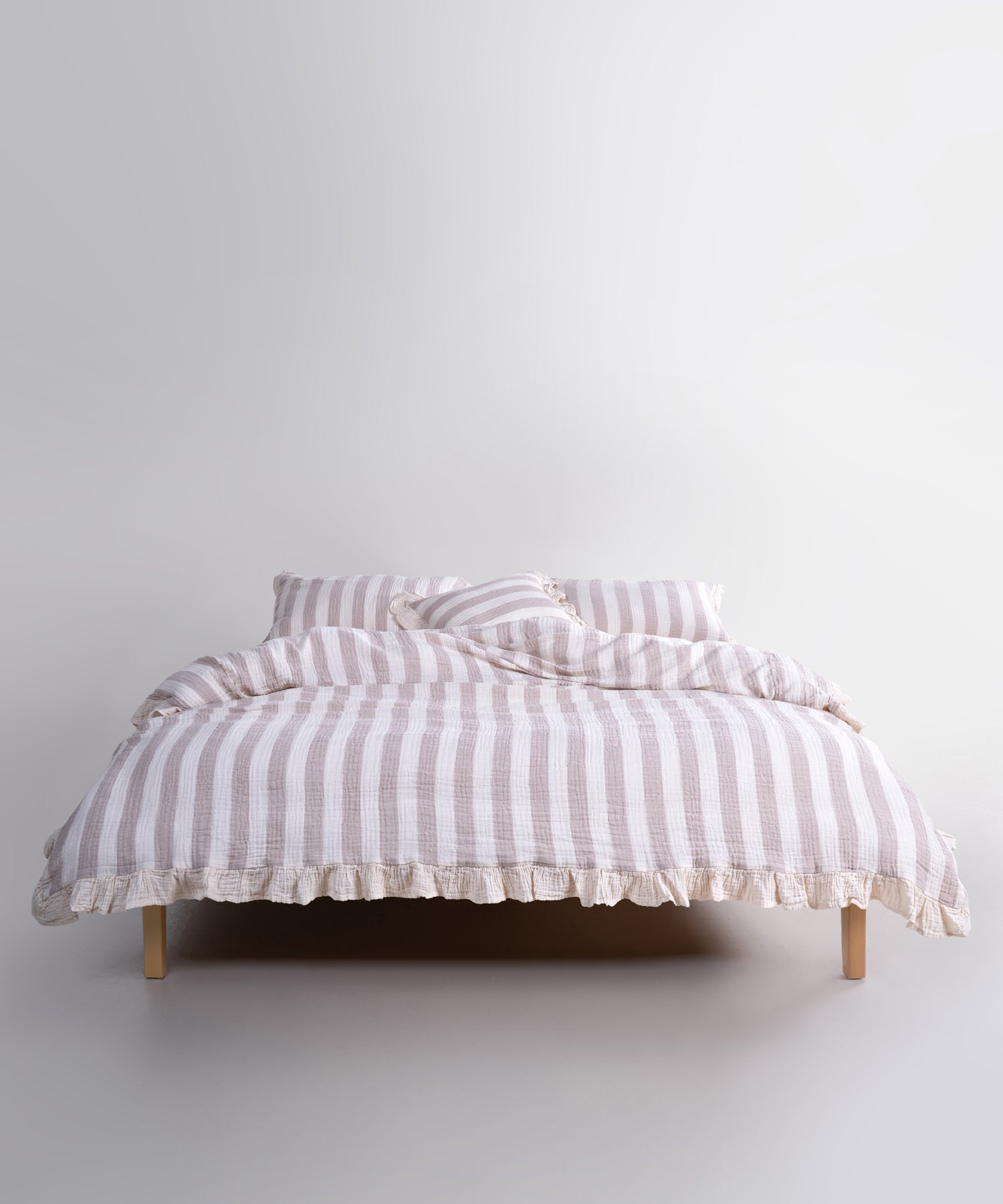 Beige striped 100% cotton muslin duvet cover set displayed on bed, garment washed breathable bedding with natural texture and ruffled edges