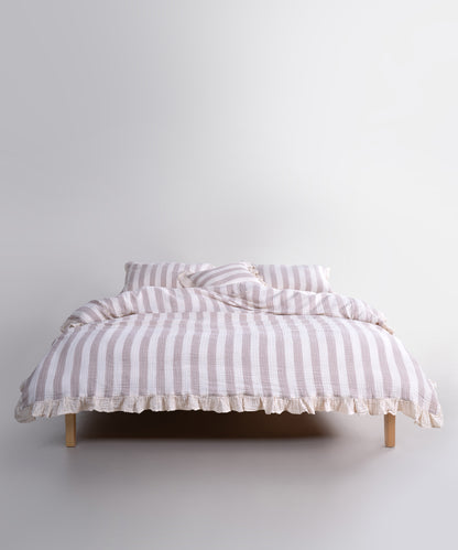 Beige striped 100% cotton muslin duvet cover set displayed on bed, garment washed breathable bedding with natural texture and ruffled edges