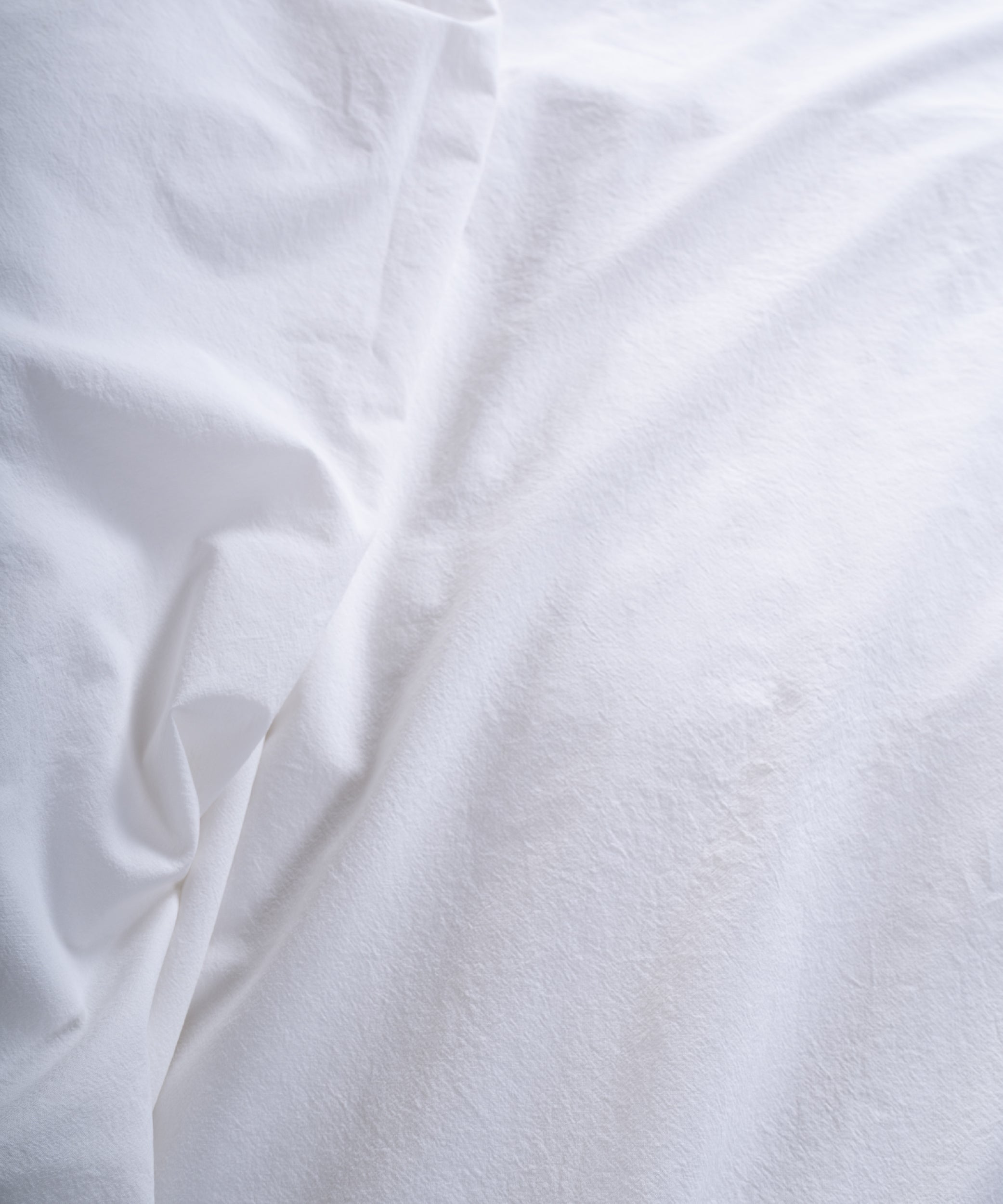 Soft stonewashed white cotton fitted sheet styled on modern bedroom bed, breathable natural cotton bedding for all seasons.