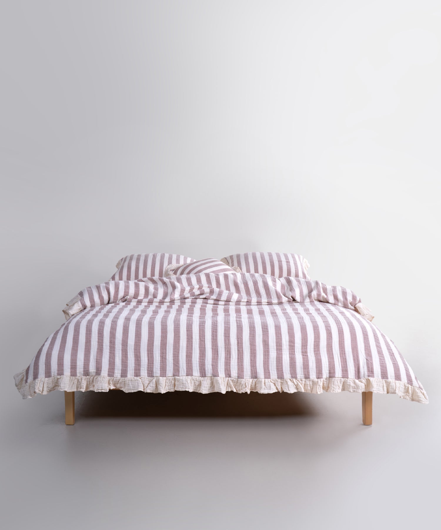 Brown striped cotton muslin duvet cover set displayed on bed, garment washed breathable bedding with natural cream base