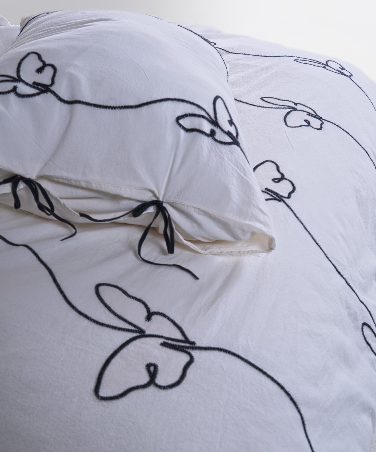 Close-up of the butterfly embroidery on the Snow White stonewashed cotton duvet cover set, showing the delicate stitched detail.