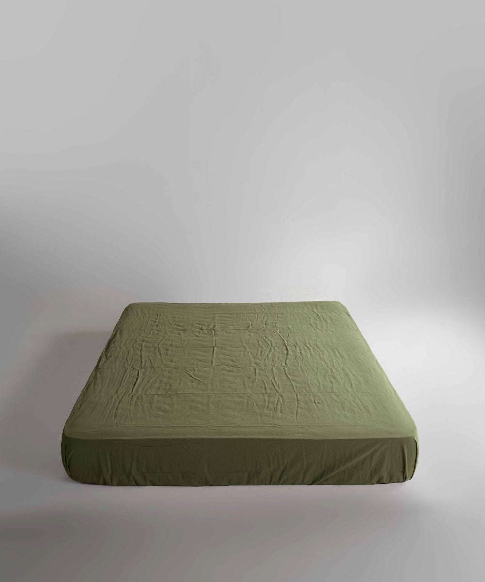 Soft stonewashed cotton fitted sheet in Capulet Olive Green. Secure elastic fit, breathable fabric and a calm natural colour for modern bedrooms.