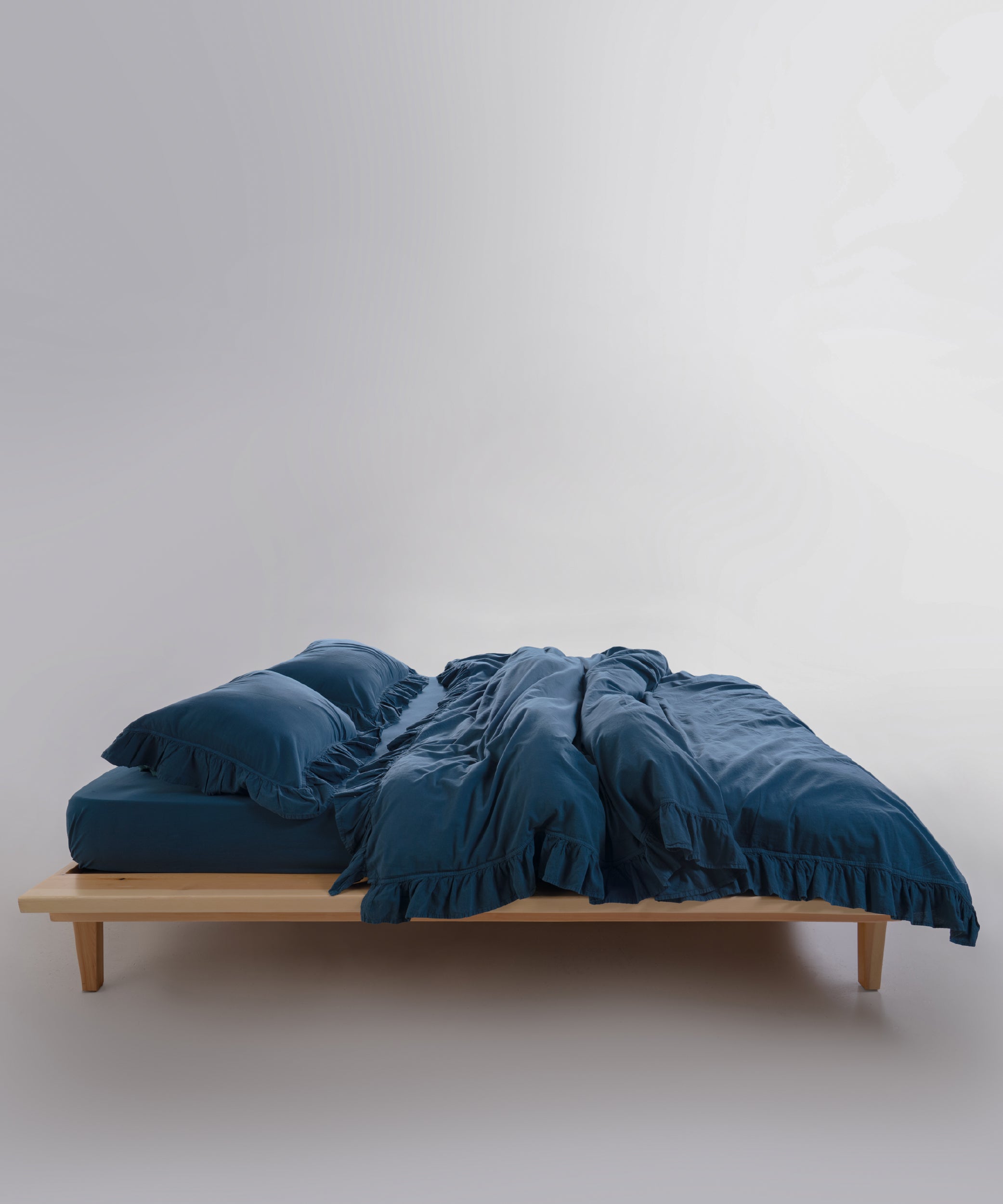 Stonewashed cotton pillowcases in dress blue featuring elegant ruffle detailing for a refined bedroom look