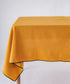 Mustard stonewashed 100% cotton tablecloth with embroidered edges on rectangular dining table, soft textured dining table linen for UK homes