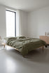 Cloud 100% Natural Cotton Gauze-Muslin Duvet Cover Set Olive on a low wooden platform bed – Limasso London