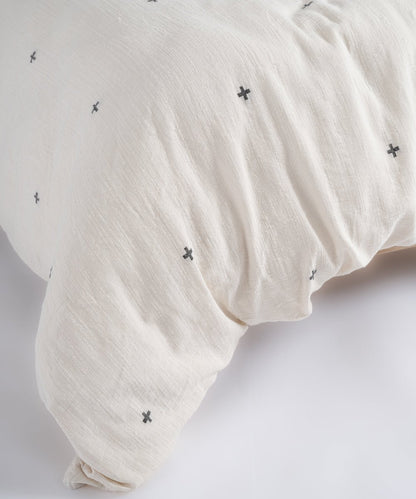 Close-up texture of breathable 100% cotton fabric with black cross pattern on natural cream base