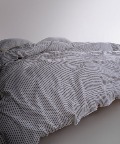 Close-up of 100% cotton garment washed fabric showing natural cream texture with fine black stripes
