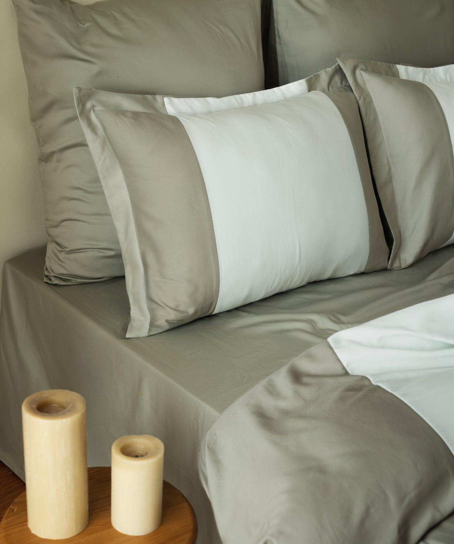Close-up of 210TC Sateen Oxford pillowcases in Mineral Green and Mint showing silky sateen sheen and candle – Limasso London
