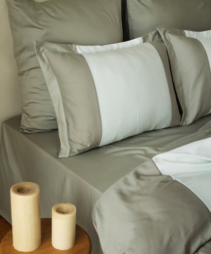 Close-up of 210TC Sateen Oxford pillowcases in Mineral Green and Mint showing silky sateen sheen and candle – Limasso London