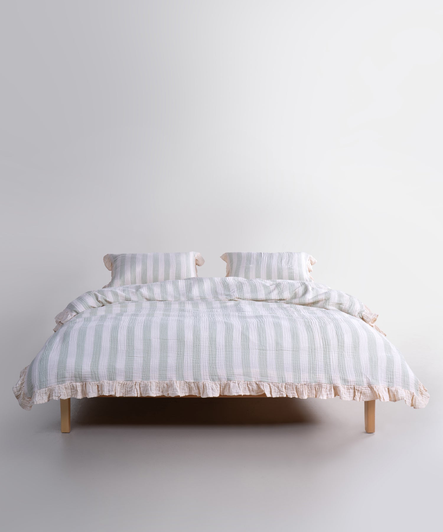Mint striped cotton muslin duvet cover set displayed on bed, garment washed breathable bedding with natural cream base