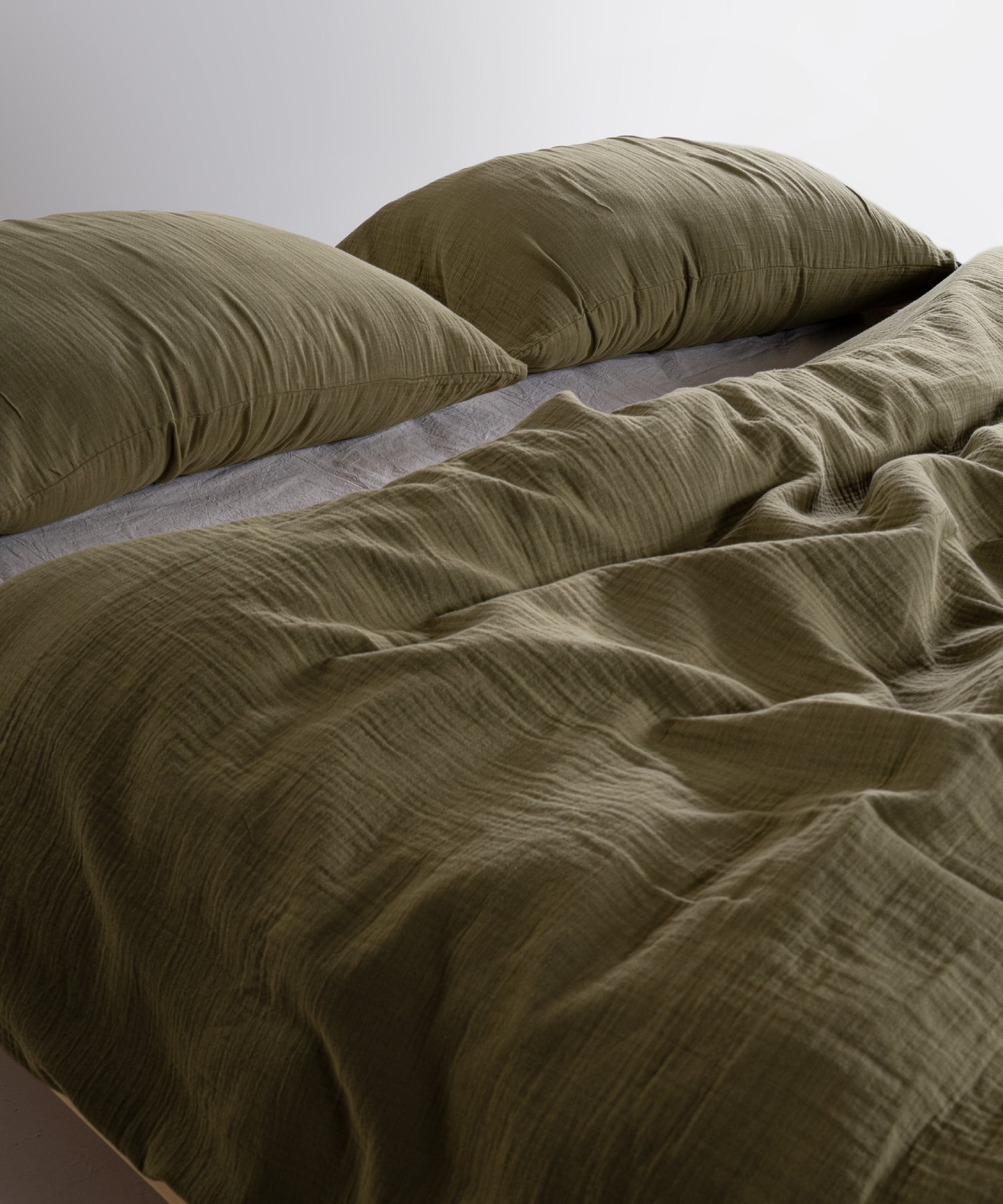 Olive green 100% cotton muslin duvet cover set with soft breathable gauze texture styled on modern UK bed