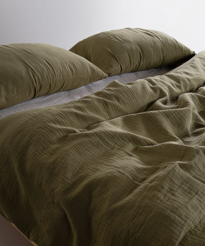Olive green 100% cotton muslin duvet cover set with soft breathable gauze texture styled on modern UK bed