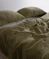 Olive green 100% cotton muslin duvet cover set with soft breathable gauze texture styled on modern UK bed