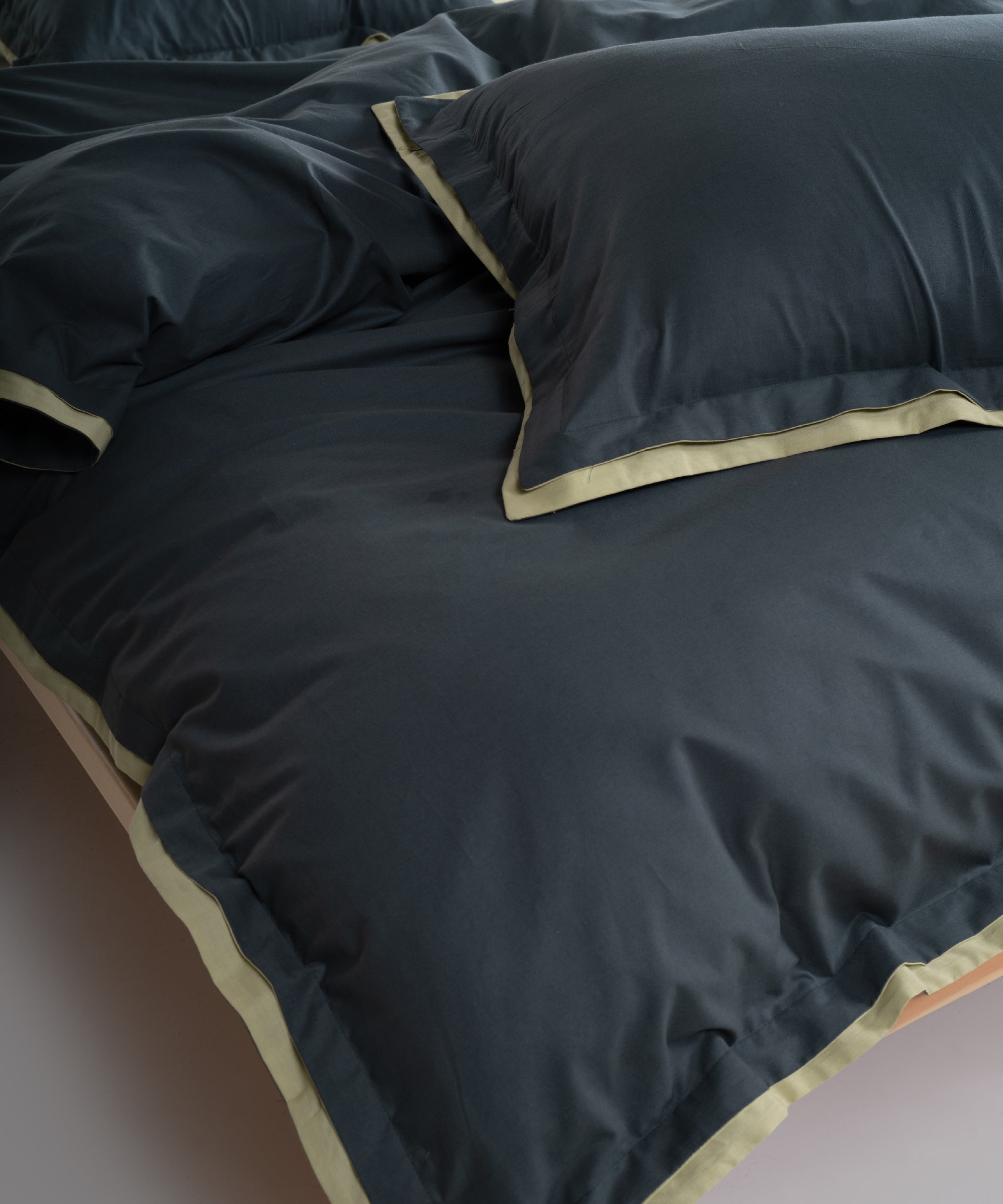 Close up of dark green cotton duvet cover with pistachio contrast Oxford border and double flange detail