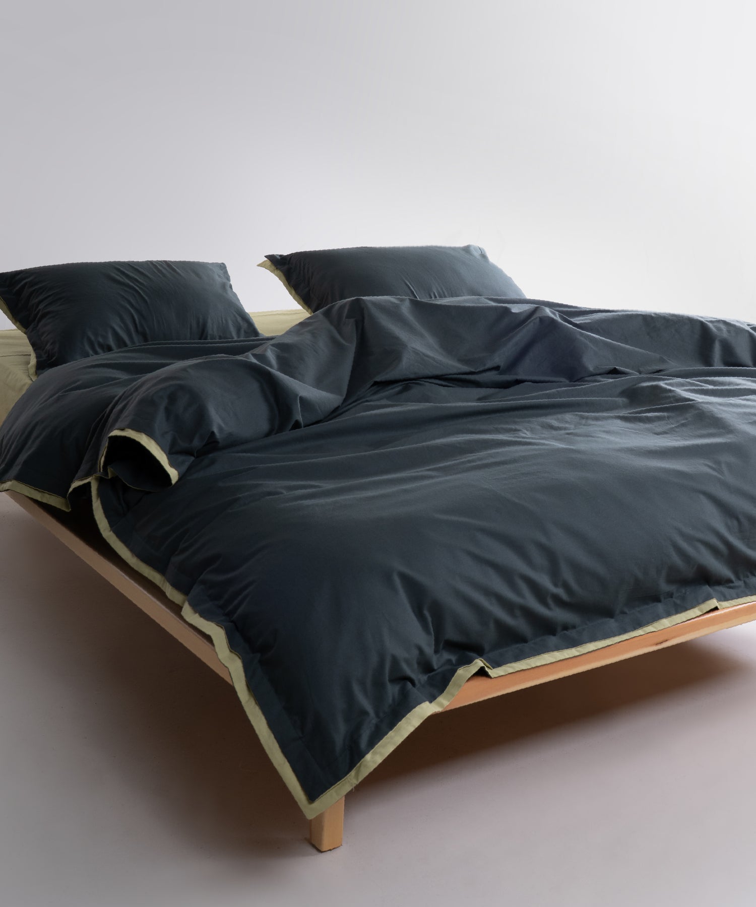 Dark green cotton pillowcases with pistachio trim and envelope closure detail