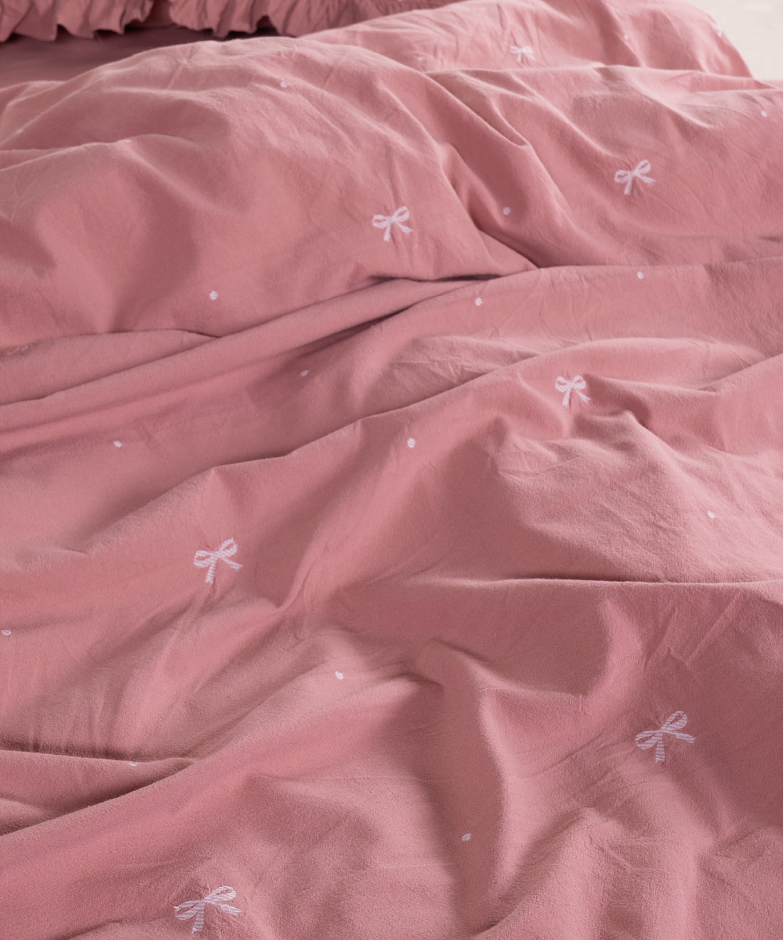 Close-up of stonewashed old rose cotton fabric with woven jacquard ribbon texture – Limasso London