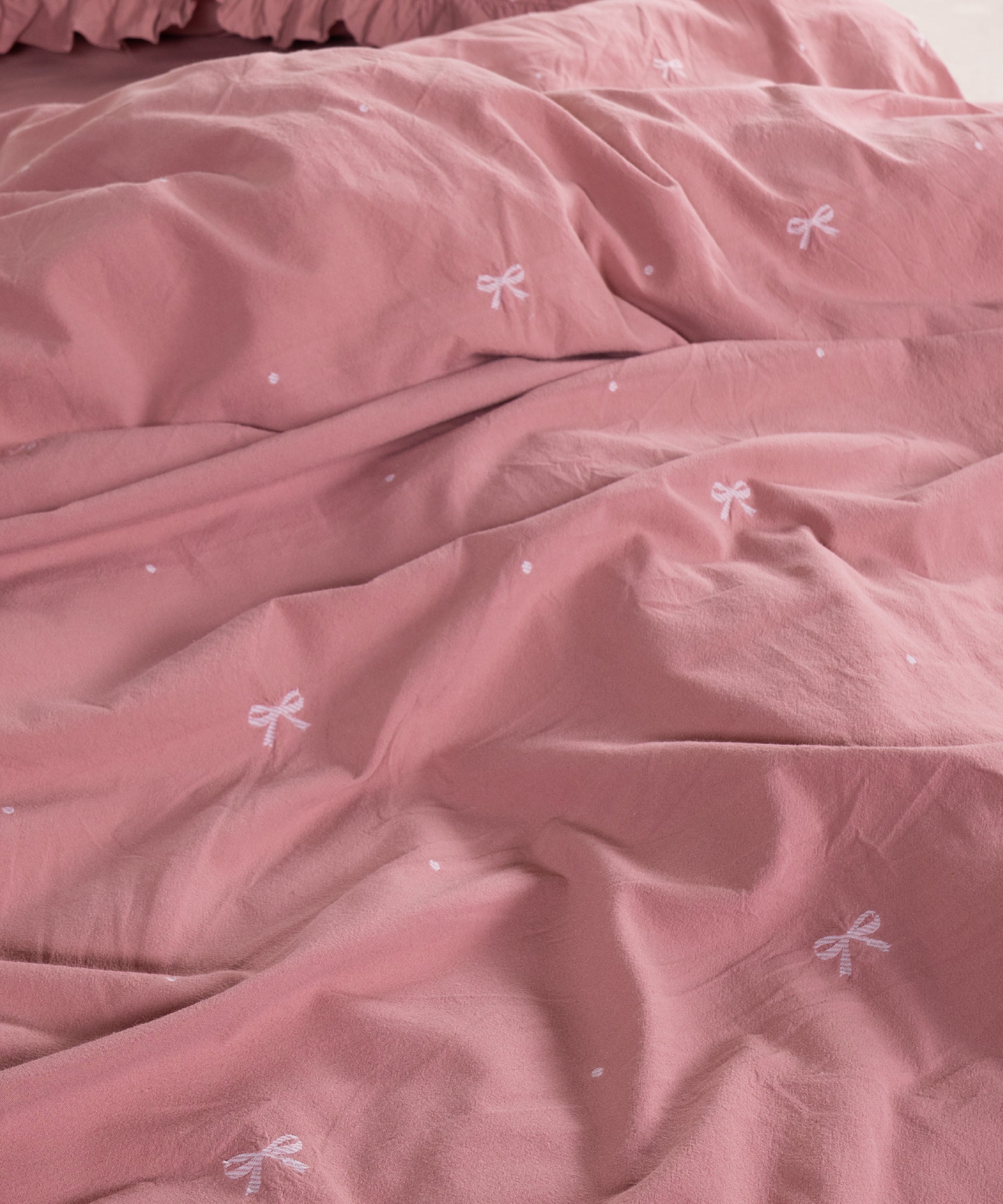 Close-up of stonewashed old rose cotton fabric with woven jacquard ribbon texture – Limasso London