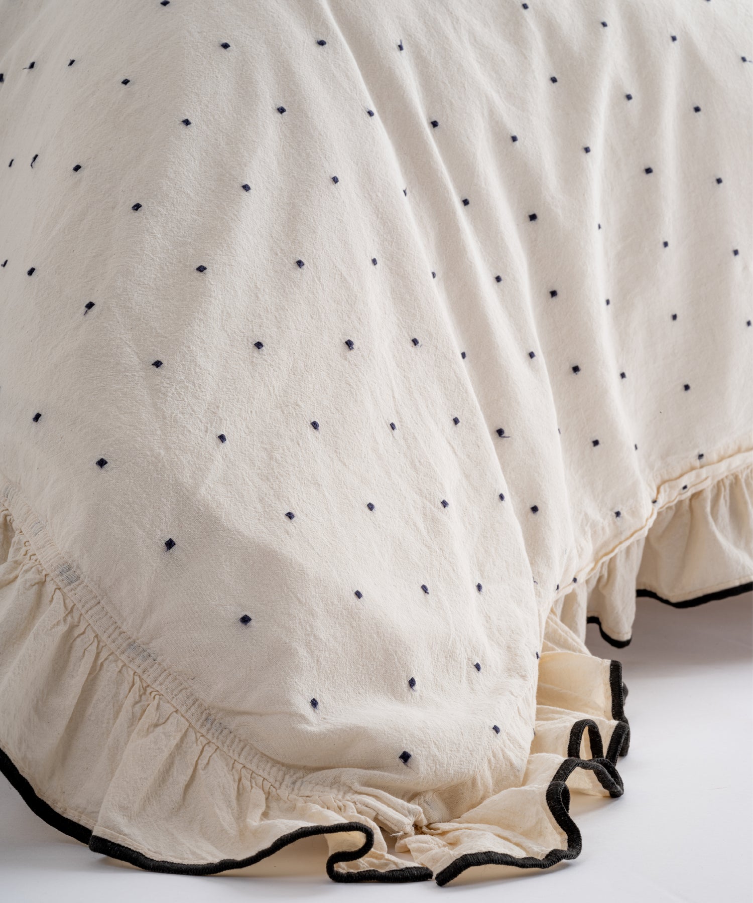 Bottom edge ruffle detail of Limasso London Point Exclusive cotton duvet cover – cream fabric with black dot embroidery and decorative ruffle finish
