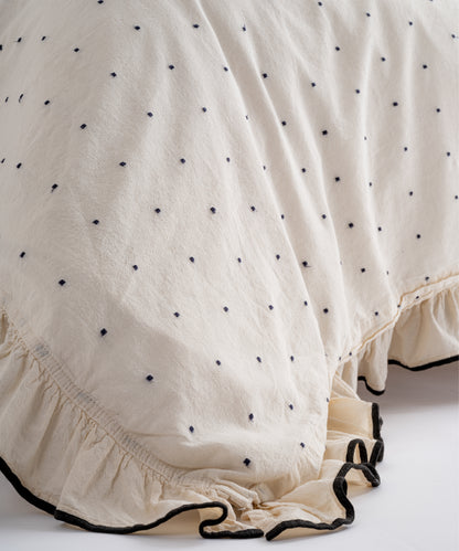Bottom edge ruffle detail of Limasso London Point Exclusive cotton duvet cover – cream fabric with black dot embroidery and decorative ruffle finish
