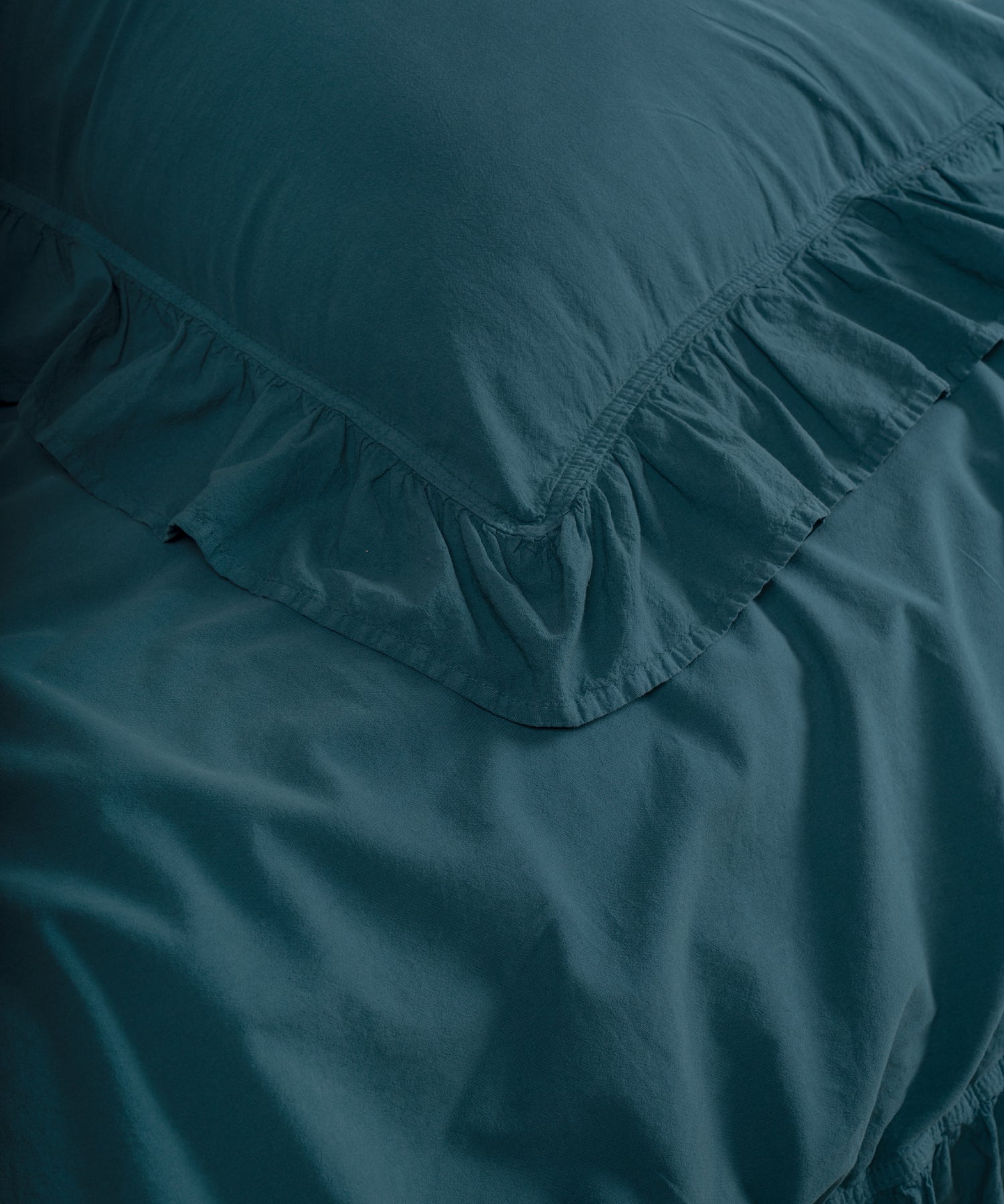 Close-up of ruffled edges on dark green stonewashed cotton pillowcase with double-needle stitching