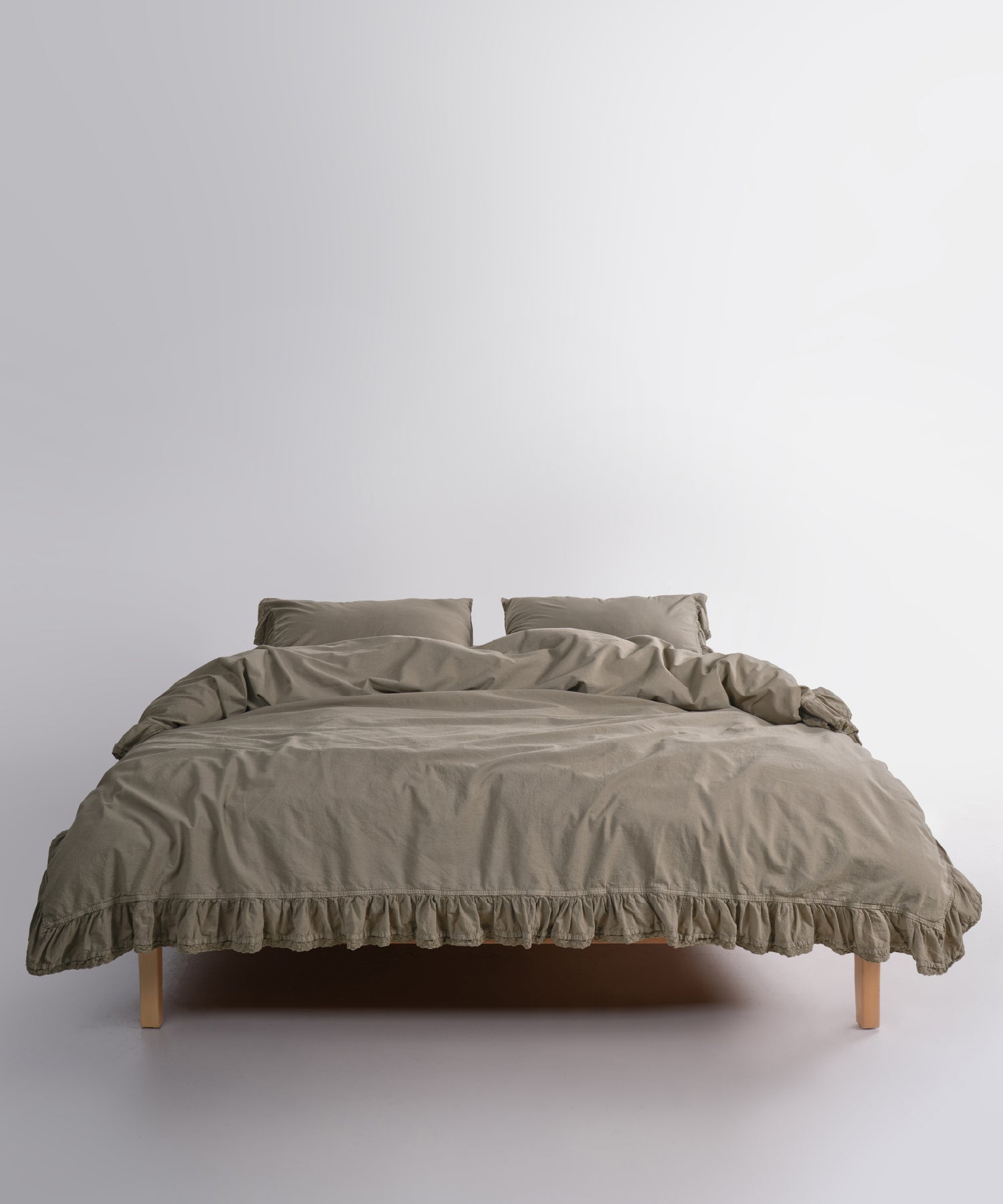 Close up of Sicilia Mediterranean Green stonewashed cotton duvet cover with elegant ruffle lace trim detail