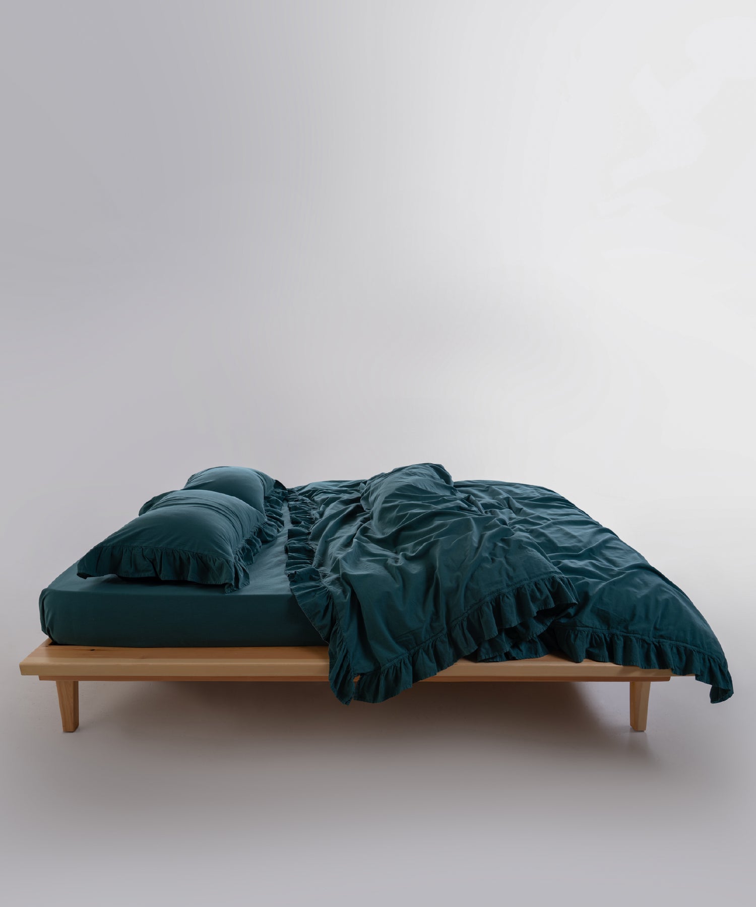Folded stonewashed cotton duvet cover in dark green highlighting softness and breathable fabric
