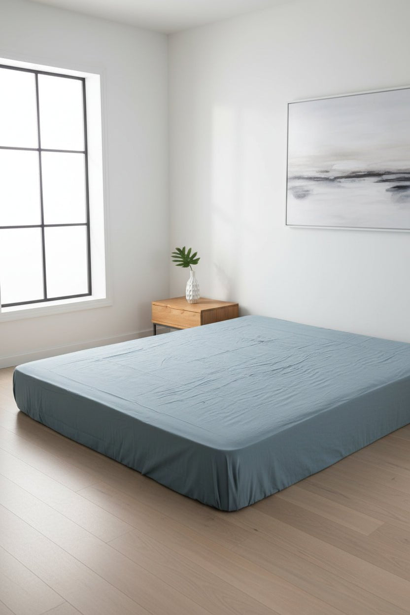 Stonewash 100% cotton fitted sheet in Med Blue colour, shown on a modern bed. Soft, breathable and naturally stonewashed for everyday comfort, designed to fit UK mattresses.