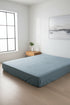 Stonewash 100% cotton fitted sheet in Med Blue colour, shown on a modern bed. Soft, breathable and naturally stonewashed for everyday comfort, designed to fit UK mattresses.