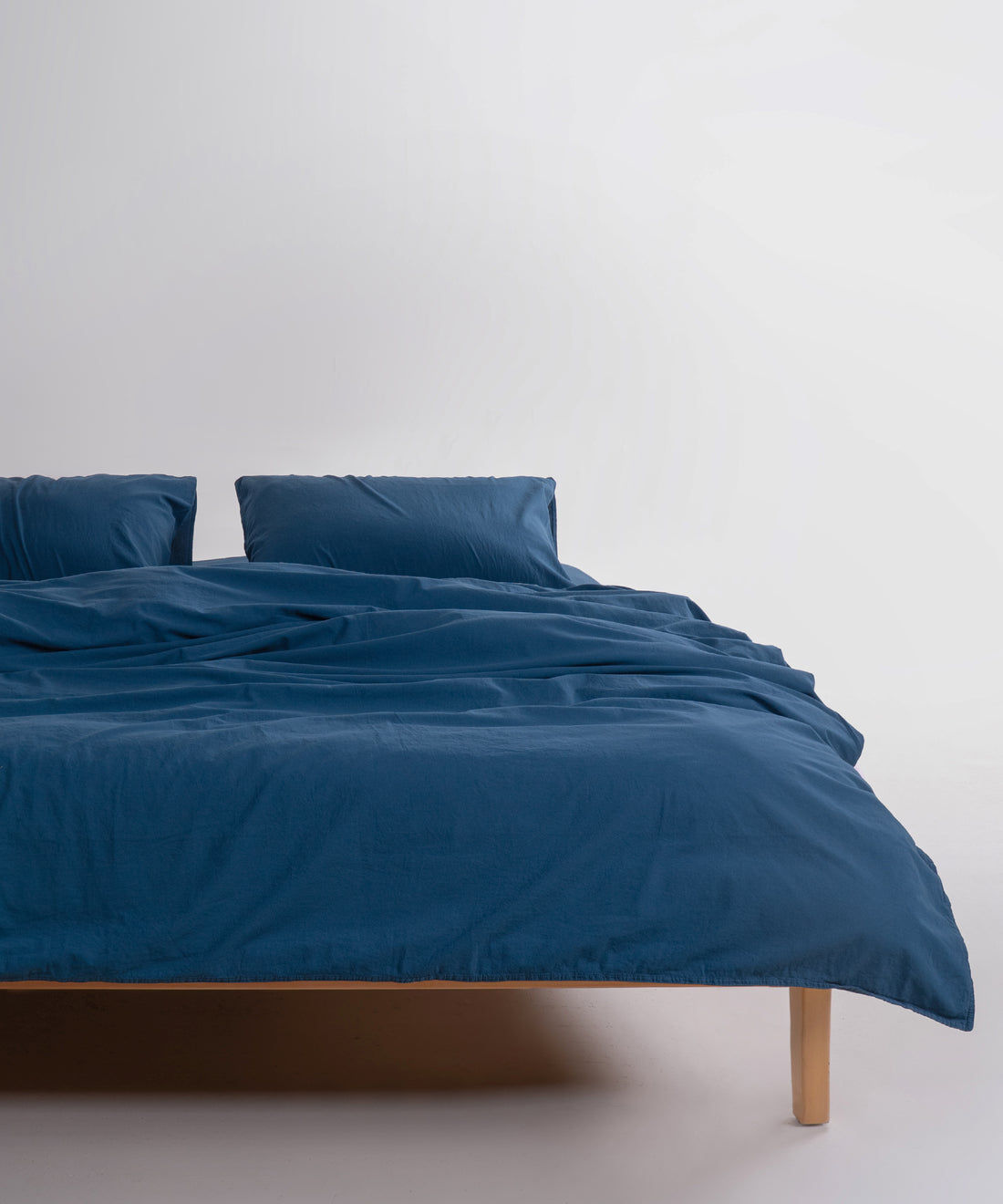 Stonewashed 100% cotton duvet cover set in dress blue, styled on a double bed in a modern UK bedroom interior