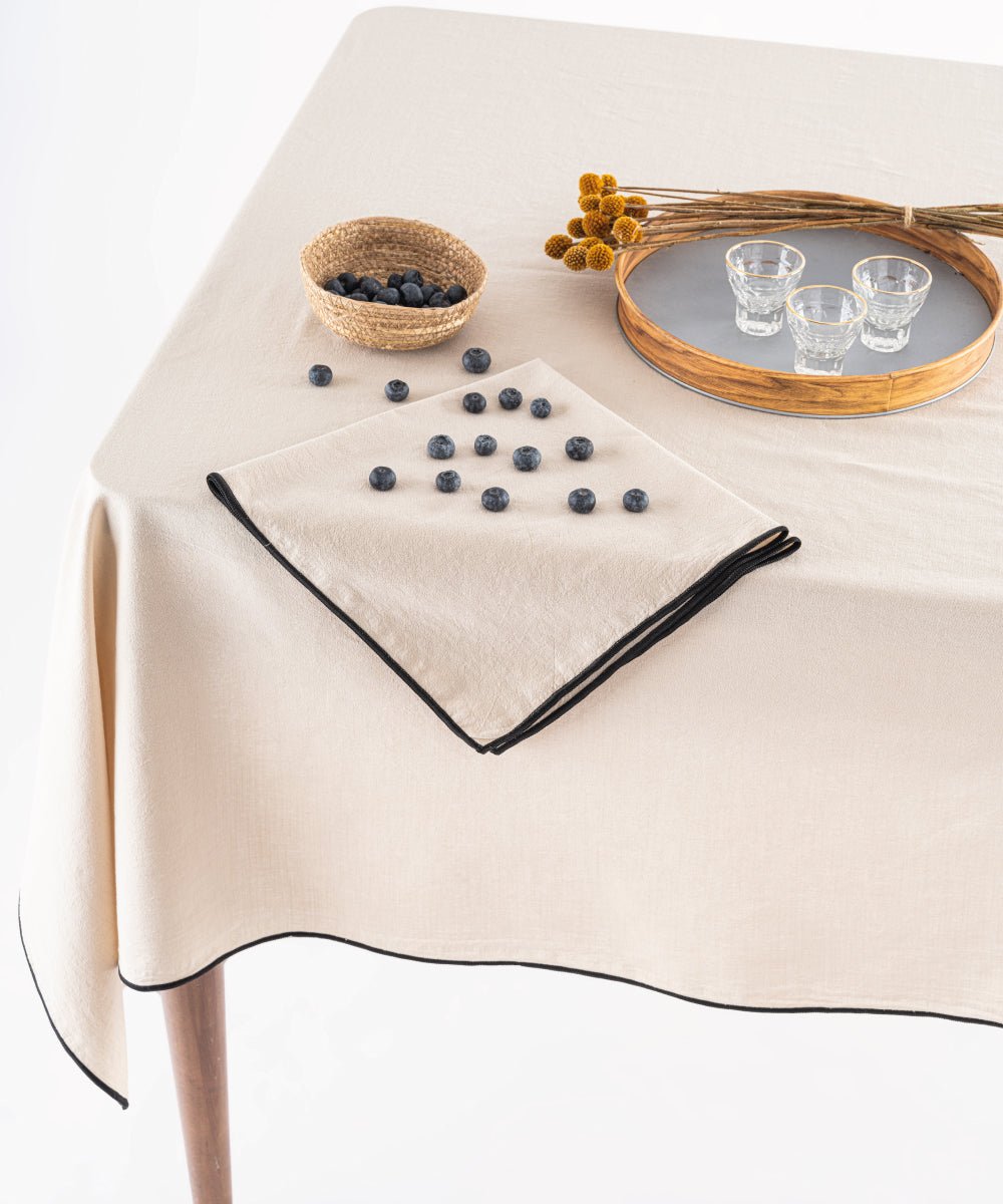 Close up of oxfordtan beige stonewashed cotton tablecloth showing soft texture and embroidered edging detail, premium UK table linen