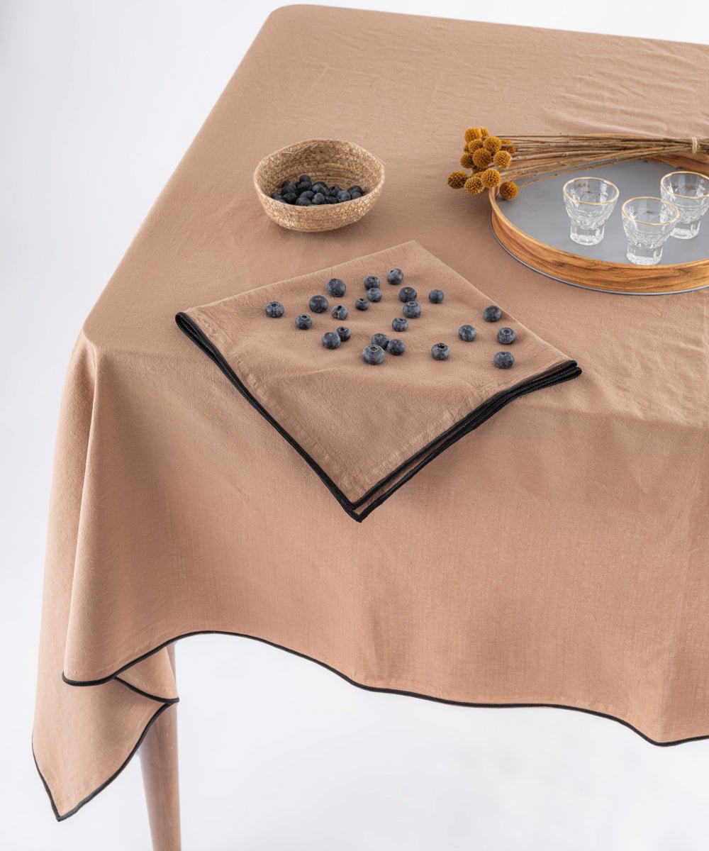 Close up of Wood Smoke grey stonewashed cotton tablecloth showing soft texture and embroidered edging detail, premium UK table linen