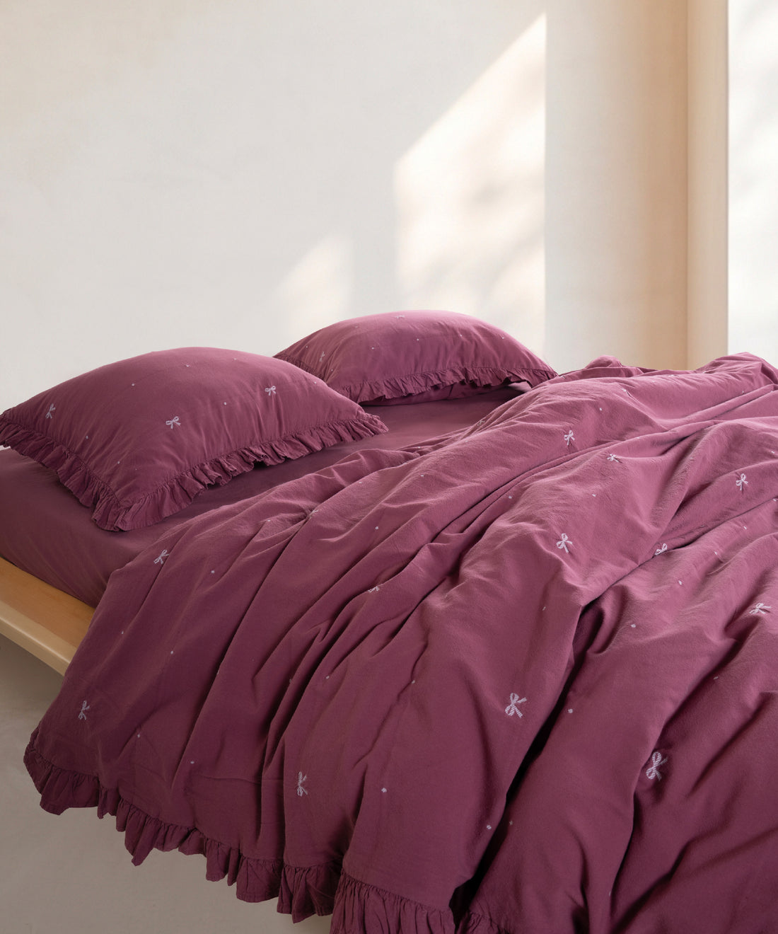 Raspberry stonewashed 100% cotton duvet cover set with ruffled edges styled on modern UK bed