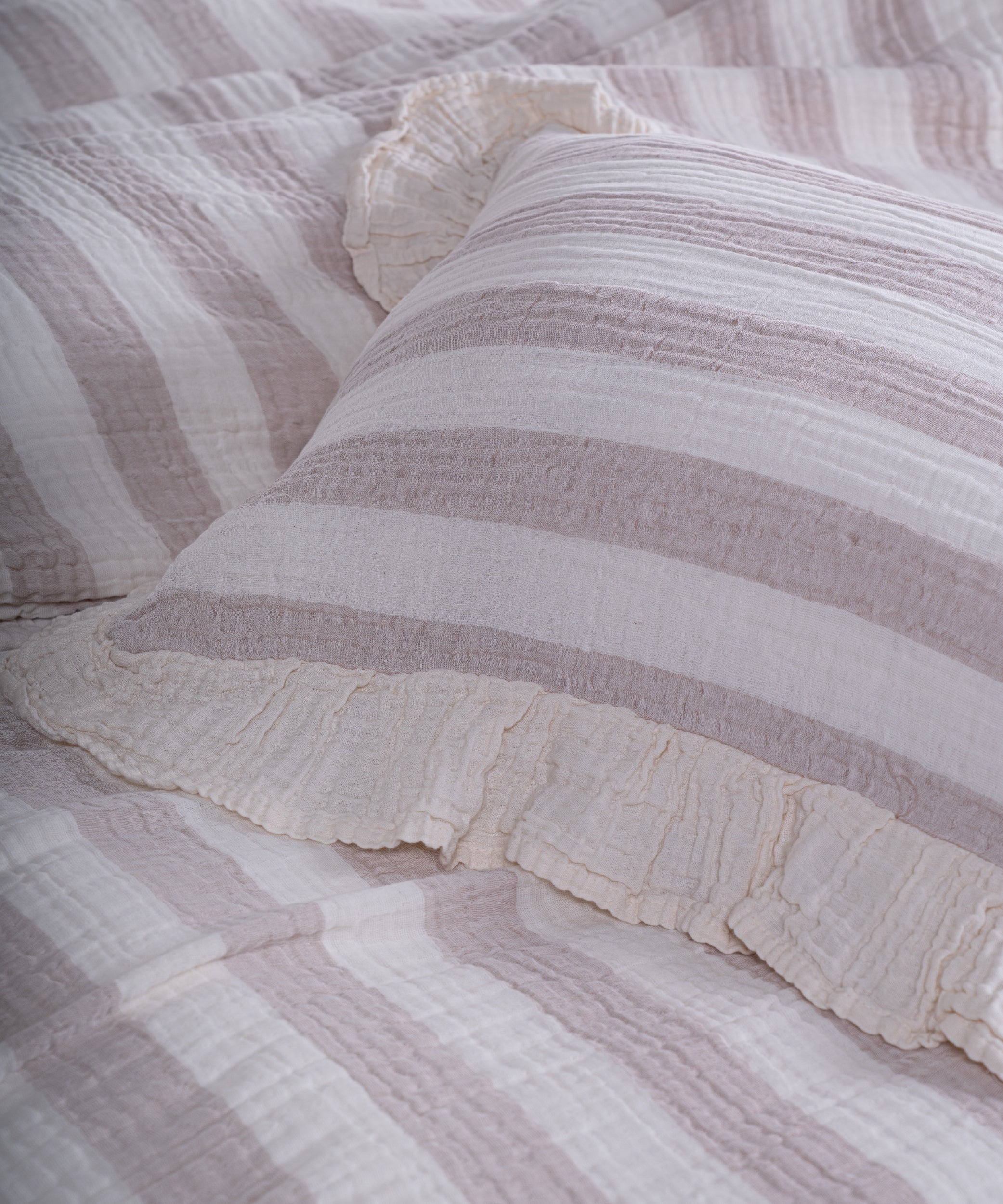 Close-up of yarn dyed 100% cotton muslin fabric with garment washed finish, natural cream base with thick beige stripes
