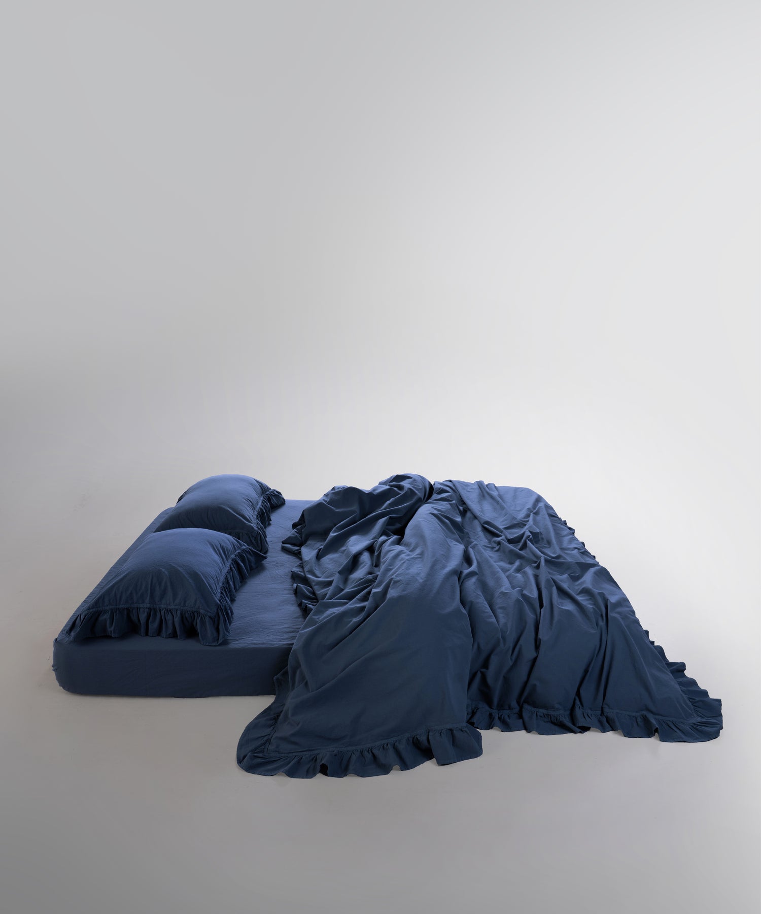 Double-stitched edges and ruffle detailing on dress blue cotton duvet cover

