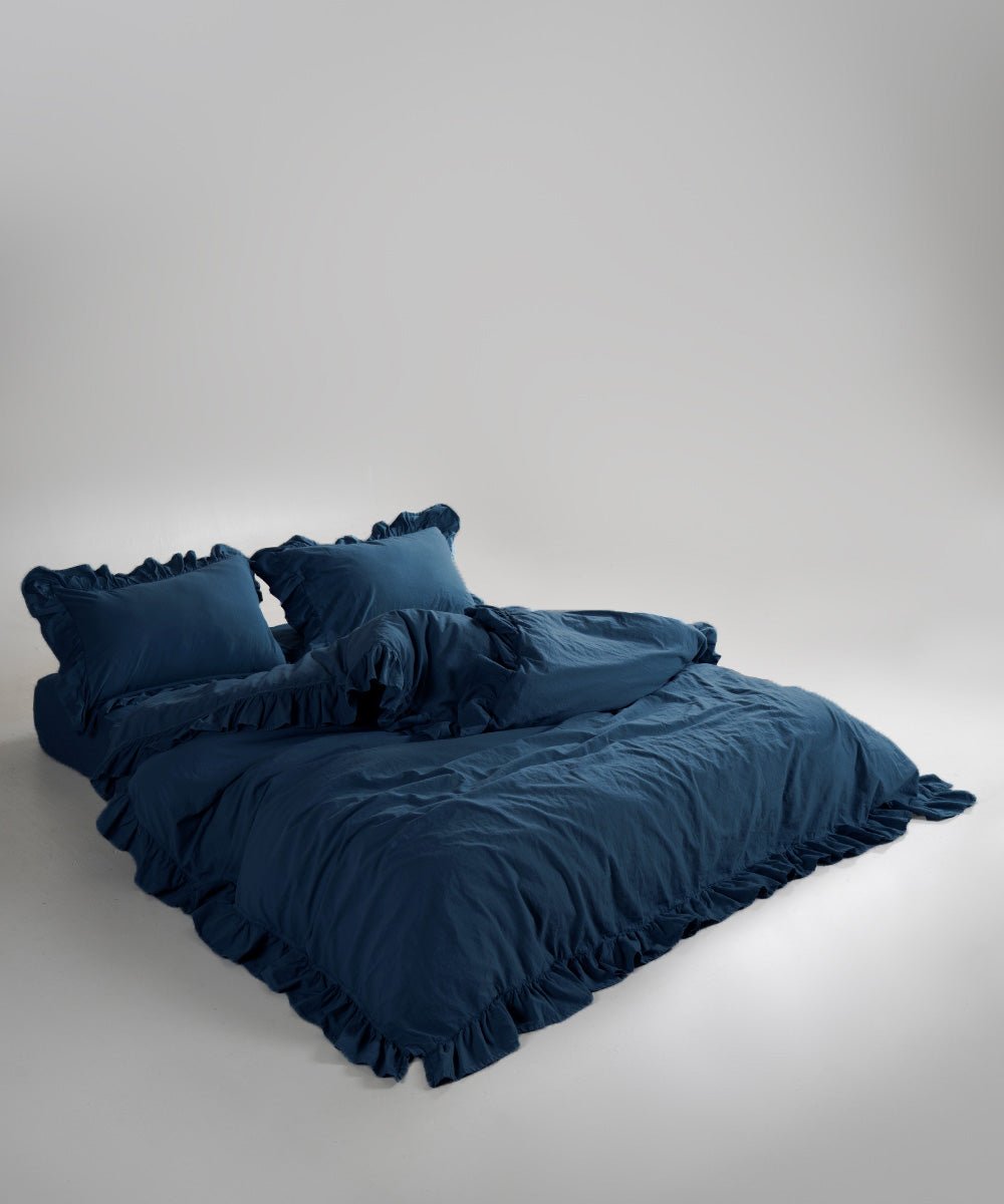 Dress blue stonewashed cotton duvet cover set displayed on bed with elegant ruffle detailing