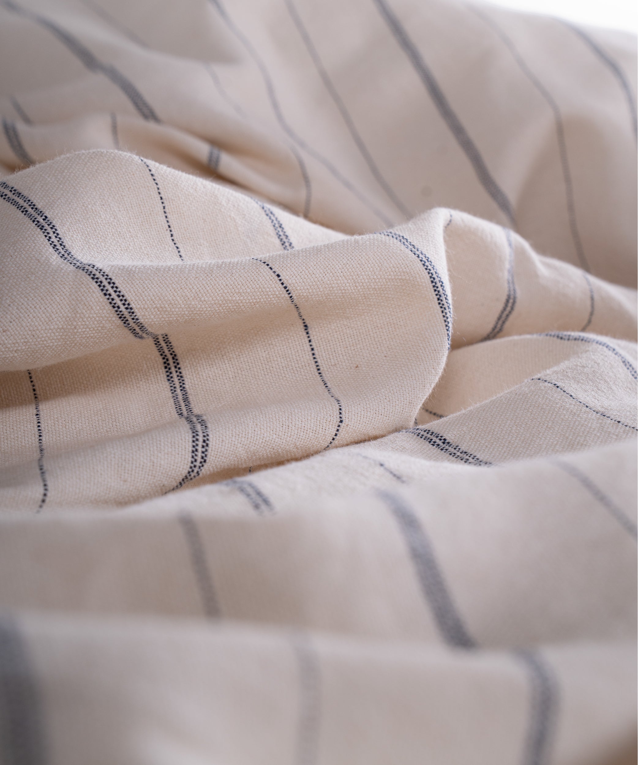Close up of garment washed cotton fabric showing natural cream base with navy stripes