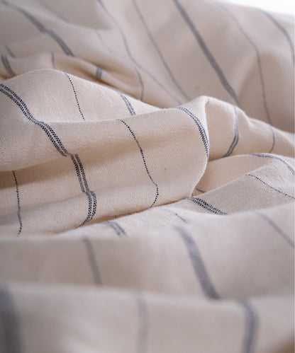 Close up of garment washed cotton fabric showing natural cream base with navy stripes